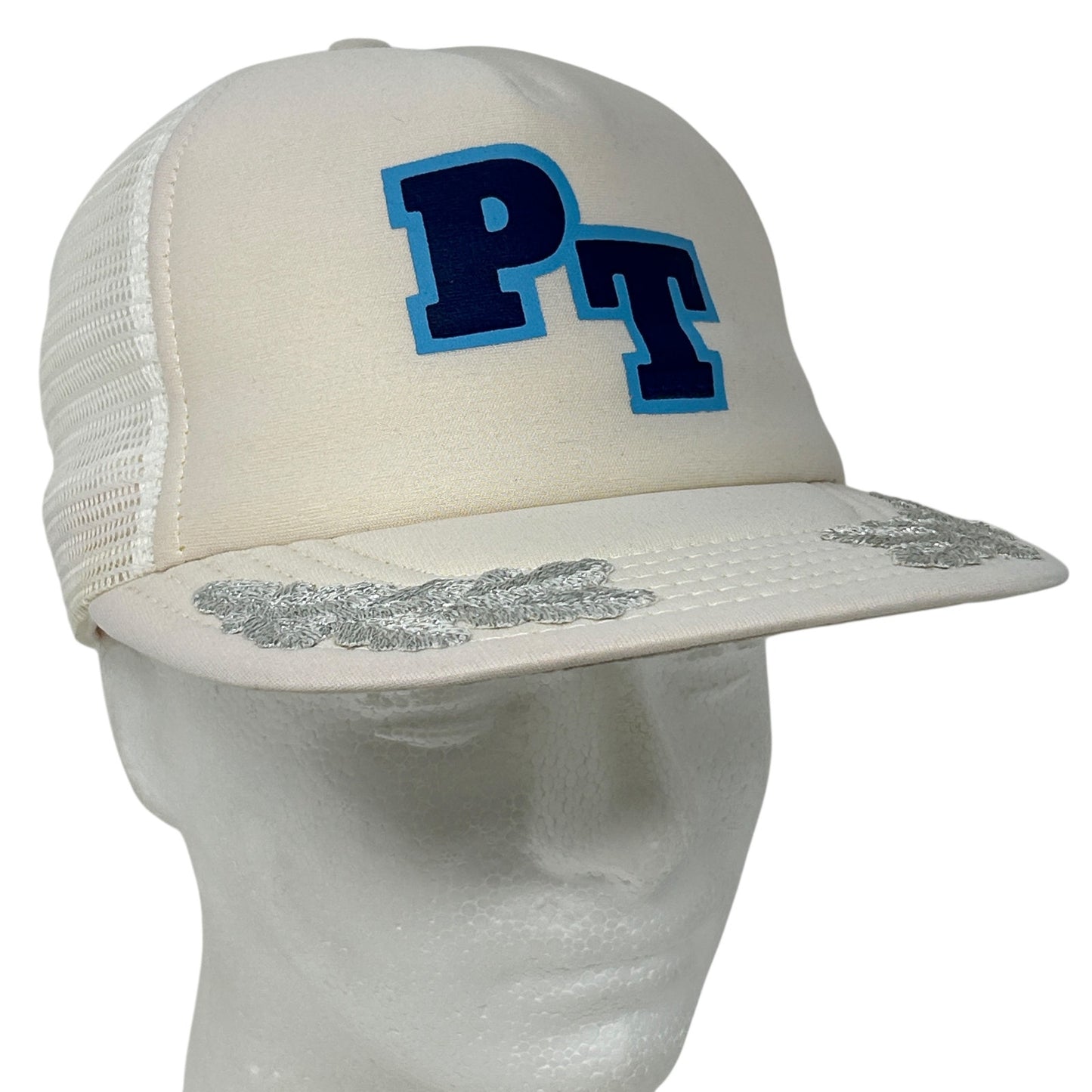 Front view of Vintage PT Trucker Hat in cream with blue PT logo and silver floral detailing