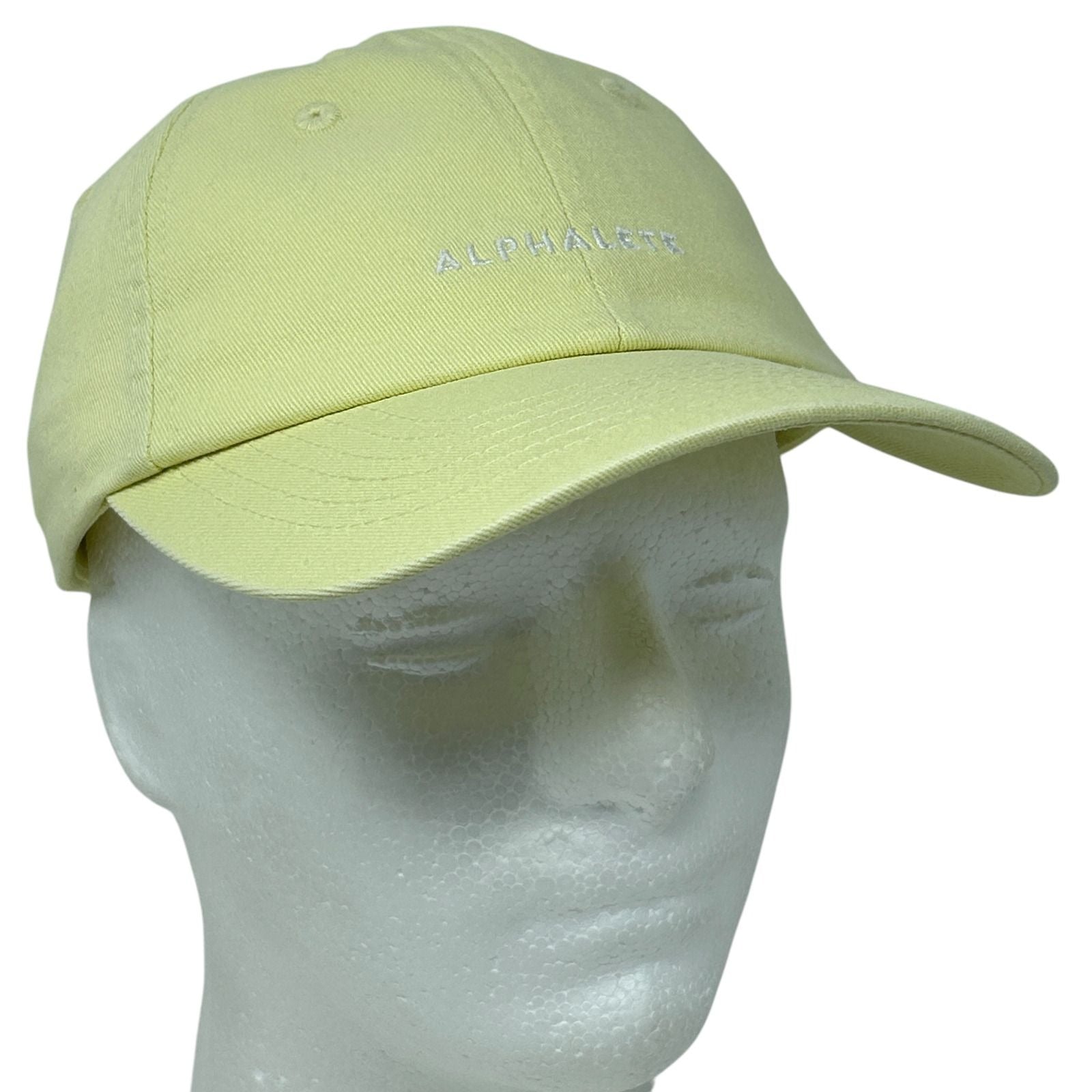 Front view of a light yellow Alphalete Athletics cap with embroidered logo on the front