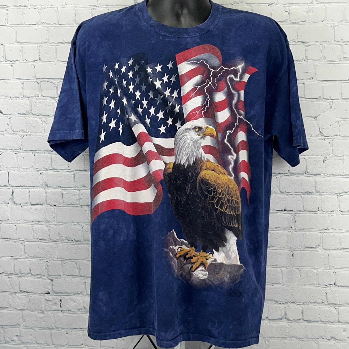 The Mountain American Flag T-Shirt featuring an eagle and stormy background in blue color