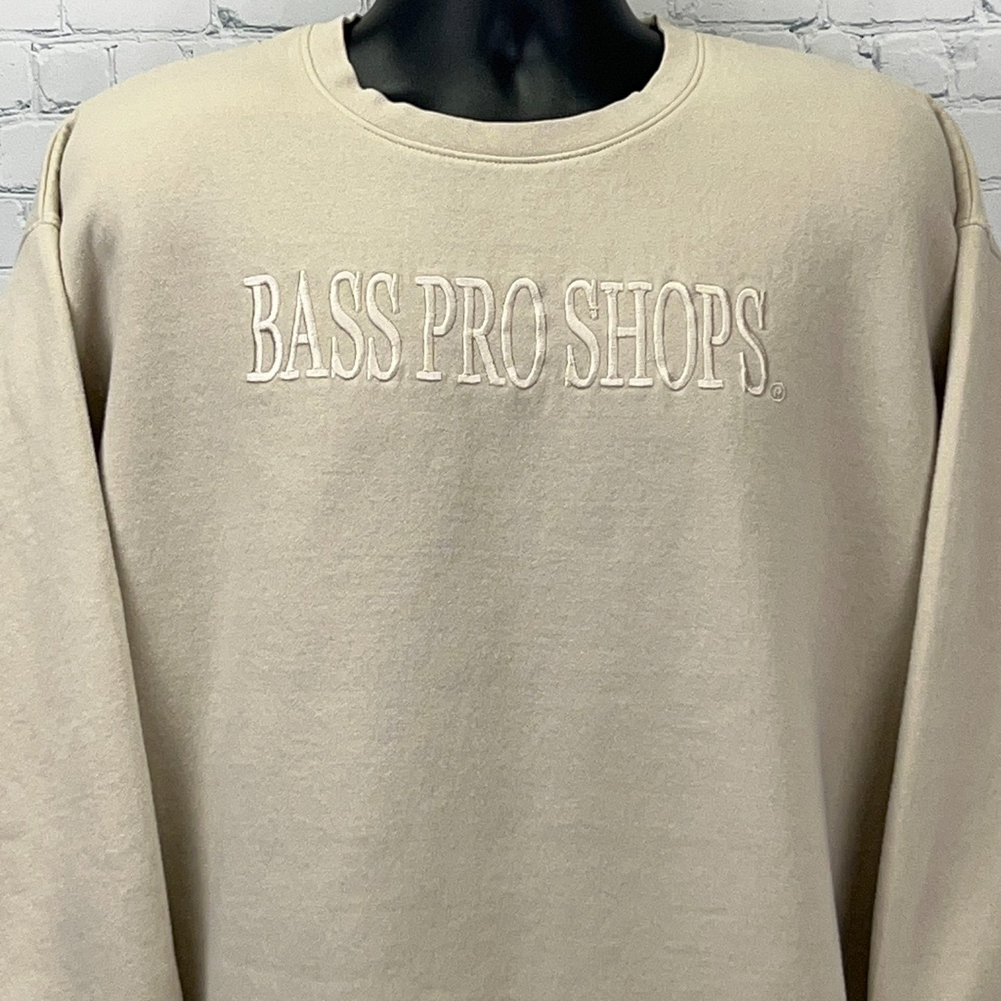 Front view of a cream-colored Bass Pro Shops sweatshirt with embroidered logo