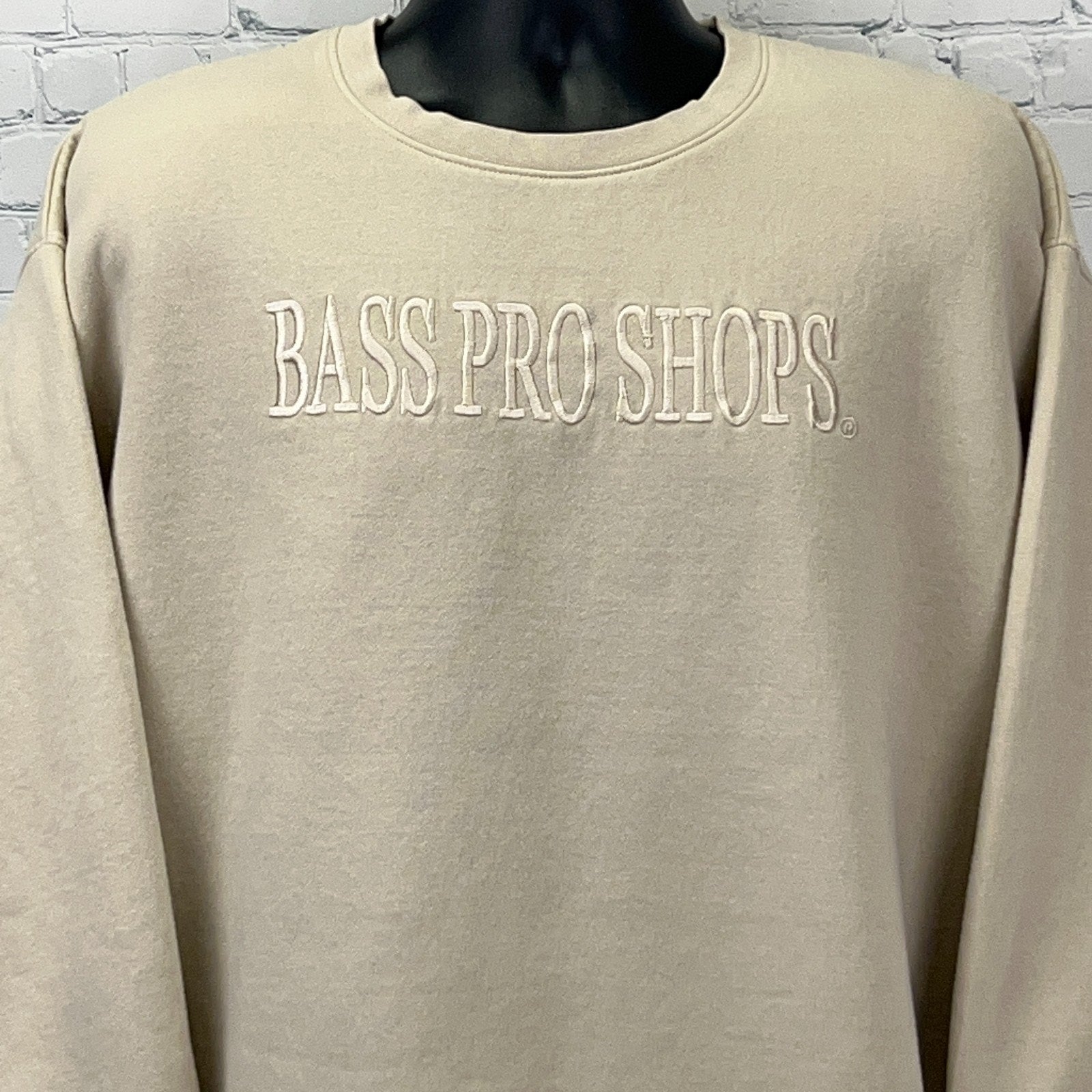 Front view of a cream-colored Bass Pro Shops sweatshirt with embroidered logo