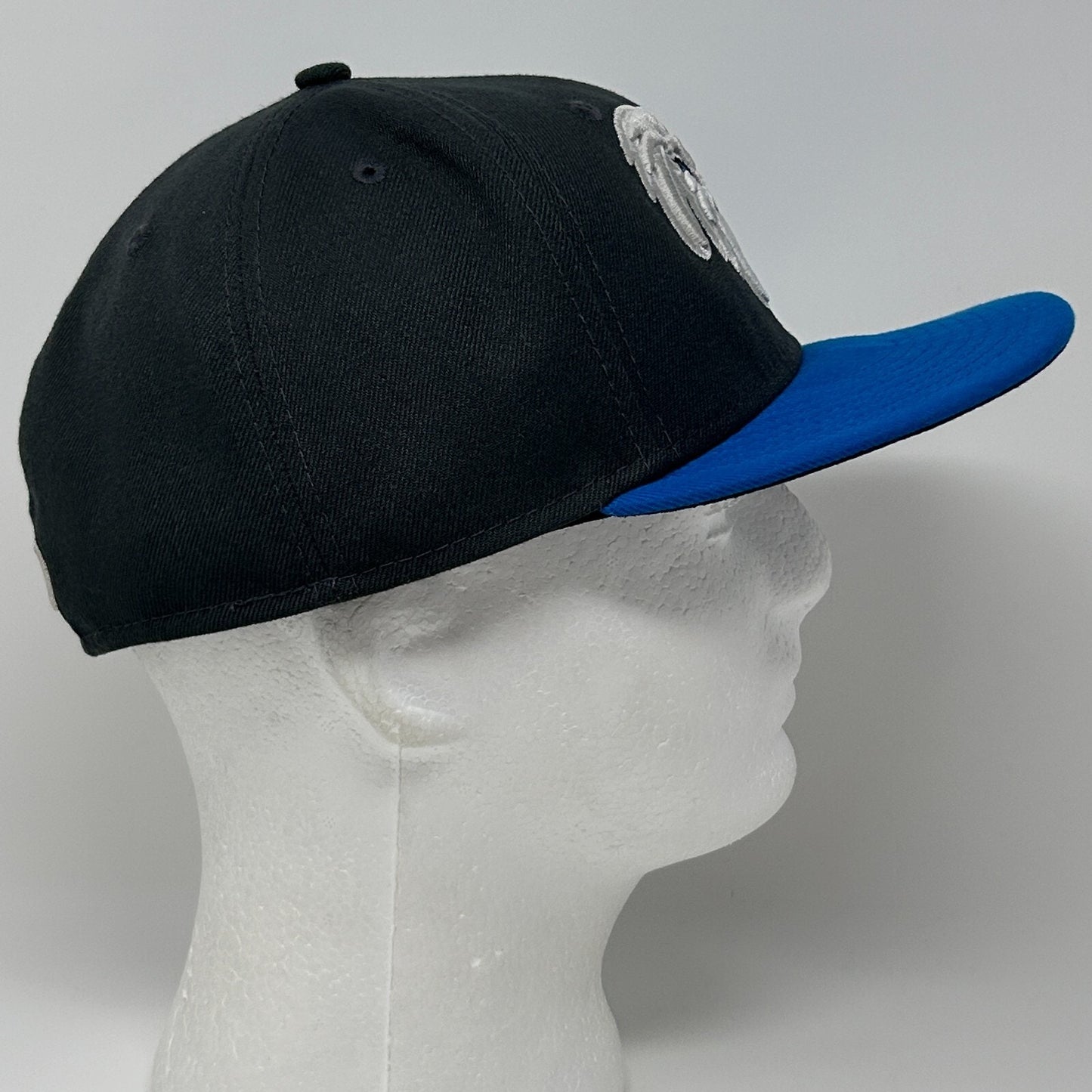 New Era baseball hat in black and blue, side view
