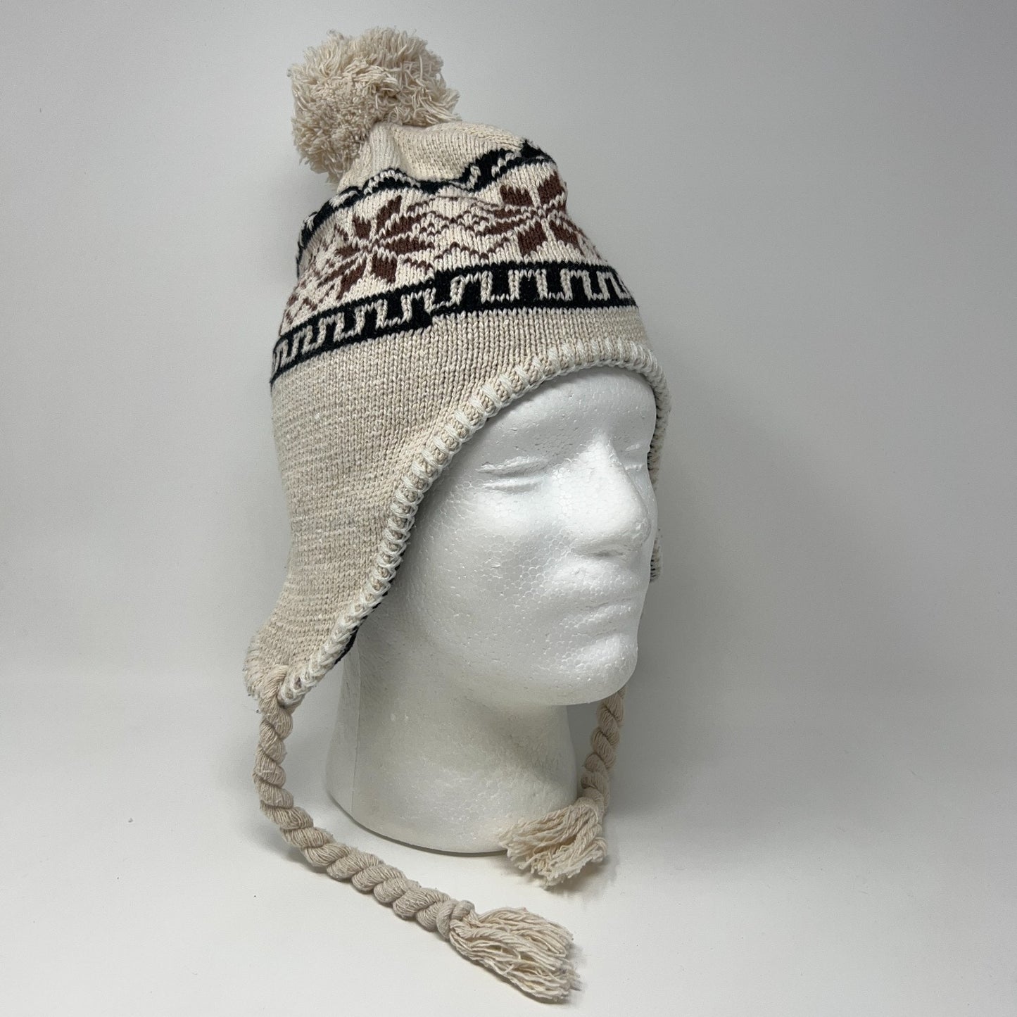 Unbranded beige beanie with pom-pom, ear flaps, and tribal pattern, shown on a mannequin head