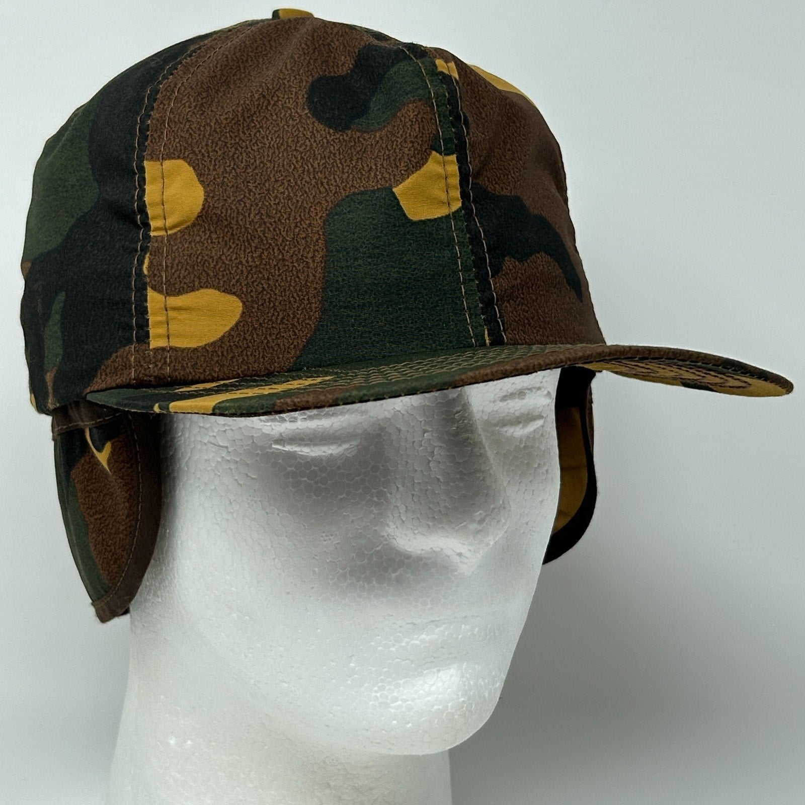 Vintage camouflage hunting hat with ear flaps in green and brown colors, front view