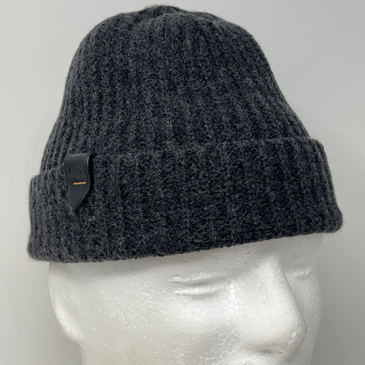 Black beanie featuring a ribbed texture and logo patch, shown from the front on a mannequin head