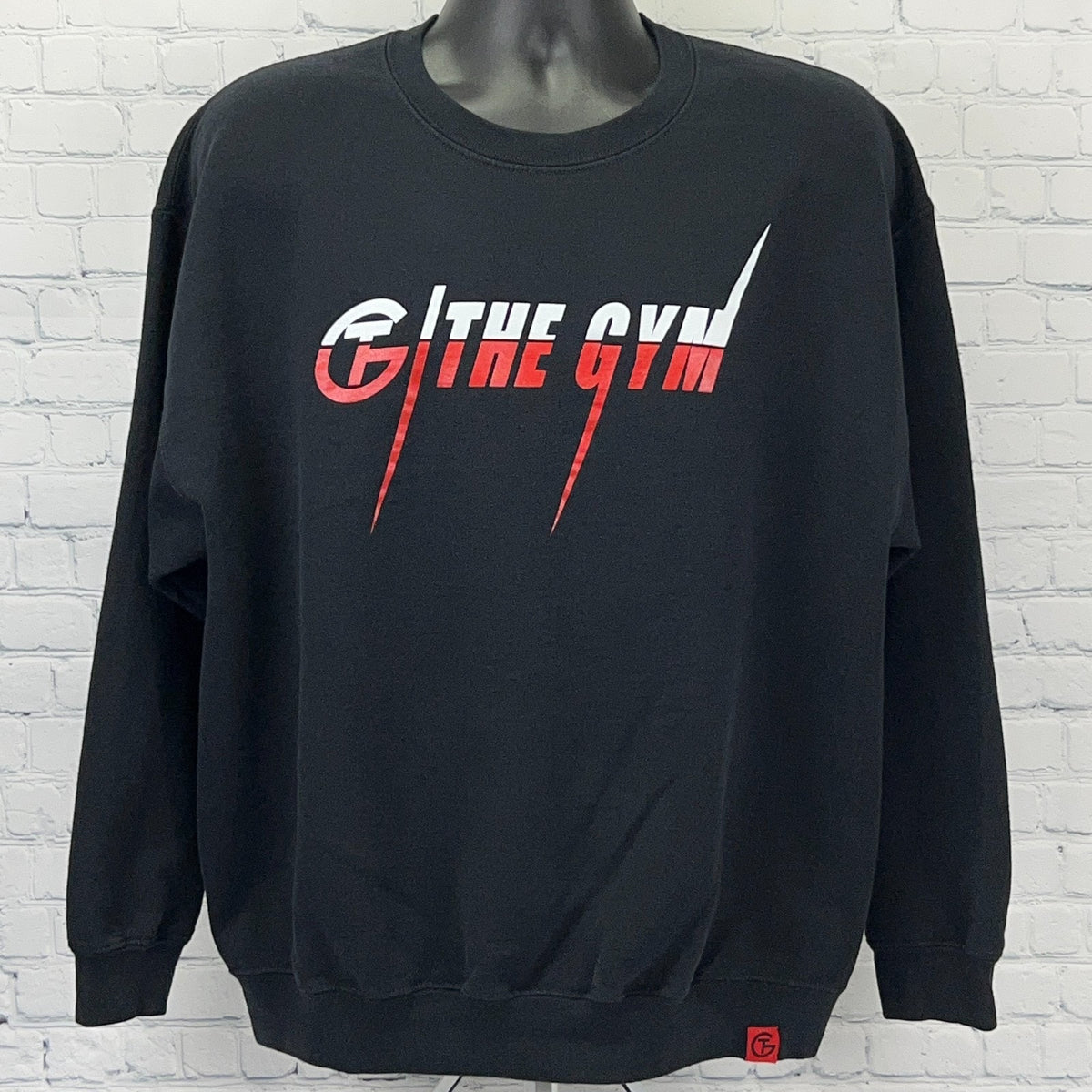 Black sweatshirt with front logo reading The Gym in red and white, featuring a relaxed fit and ribbed cuffs