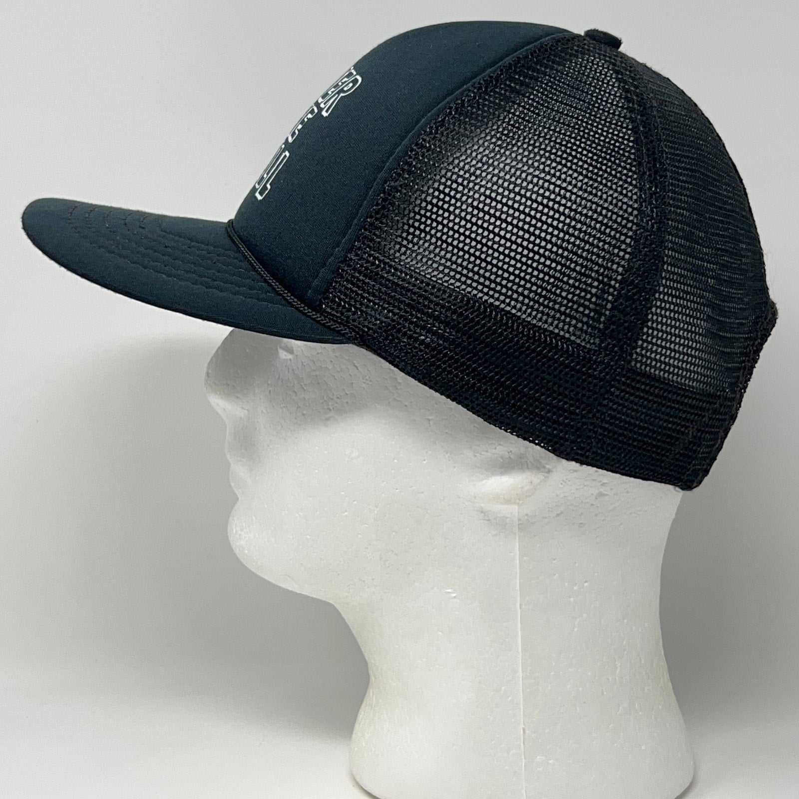 Vintage trucker cap in black, featuring a mesh back, side view
