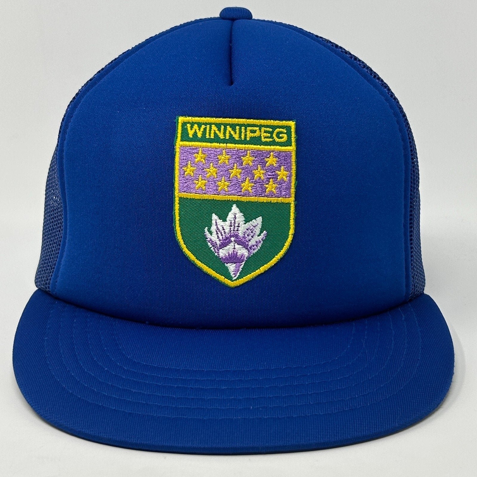 Front view of a blue Winnipeg Hat featuring an embroidered logo with a shield design