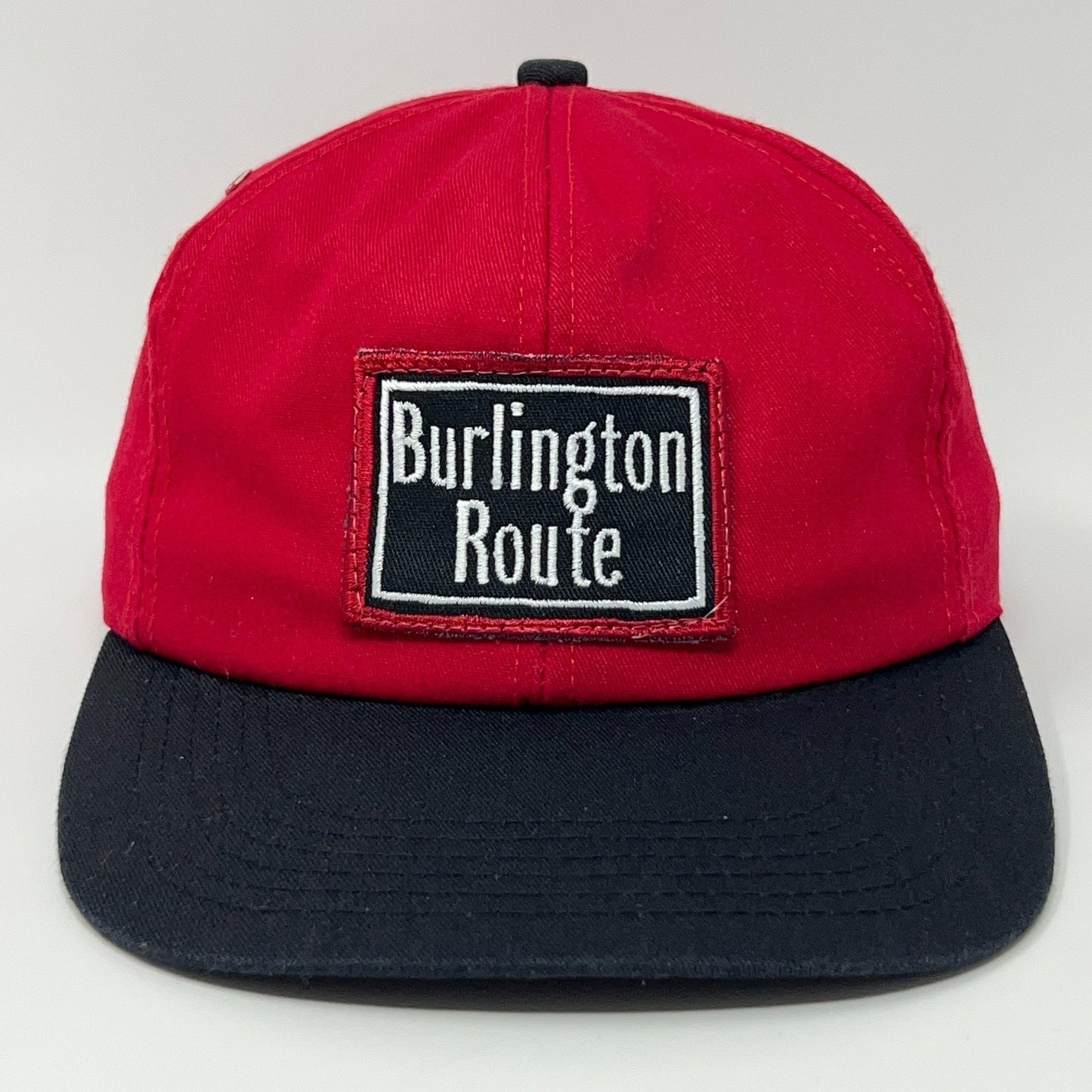 Red K-Products cap with black visor featuring Burlington Route embroidered patch on front