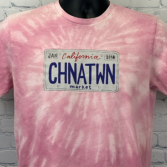 Front view of pink tie-dye T-shirt by Chinatown Market Studios with California license plate graphic