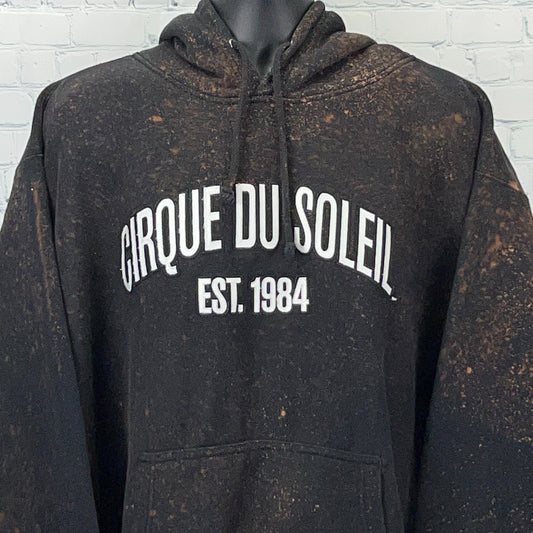 Front view of black Cirque du Soleil hoodie with distressed look and logo 'CIRQUE DU SOLEIL EST 1984'