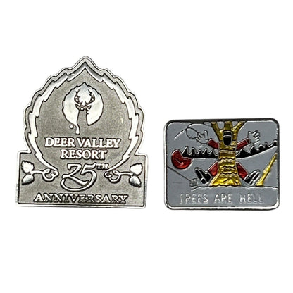 Two skiing-themed pins: a silver Deer Valley Resort 25th Anniversary pin and a colorful Trees Are Hell pin