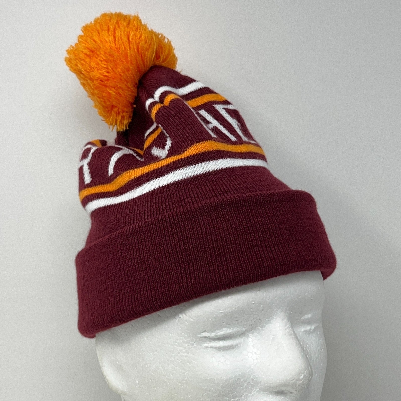 Maroon Dirty Heads beanie with orange pom-pom, featuring a striped design in white and yellow