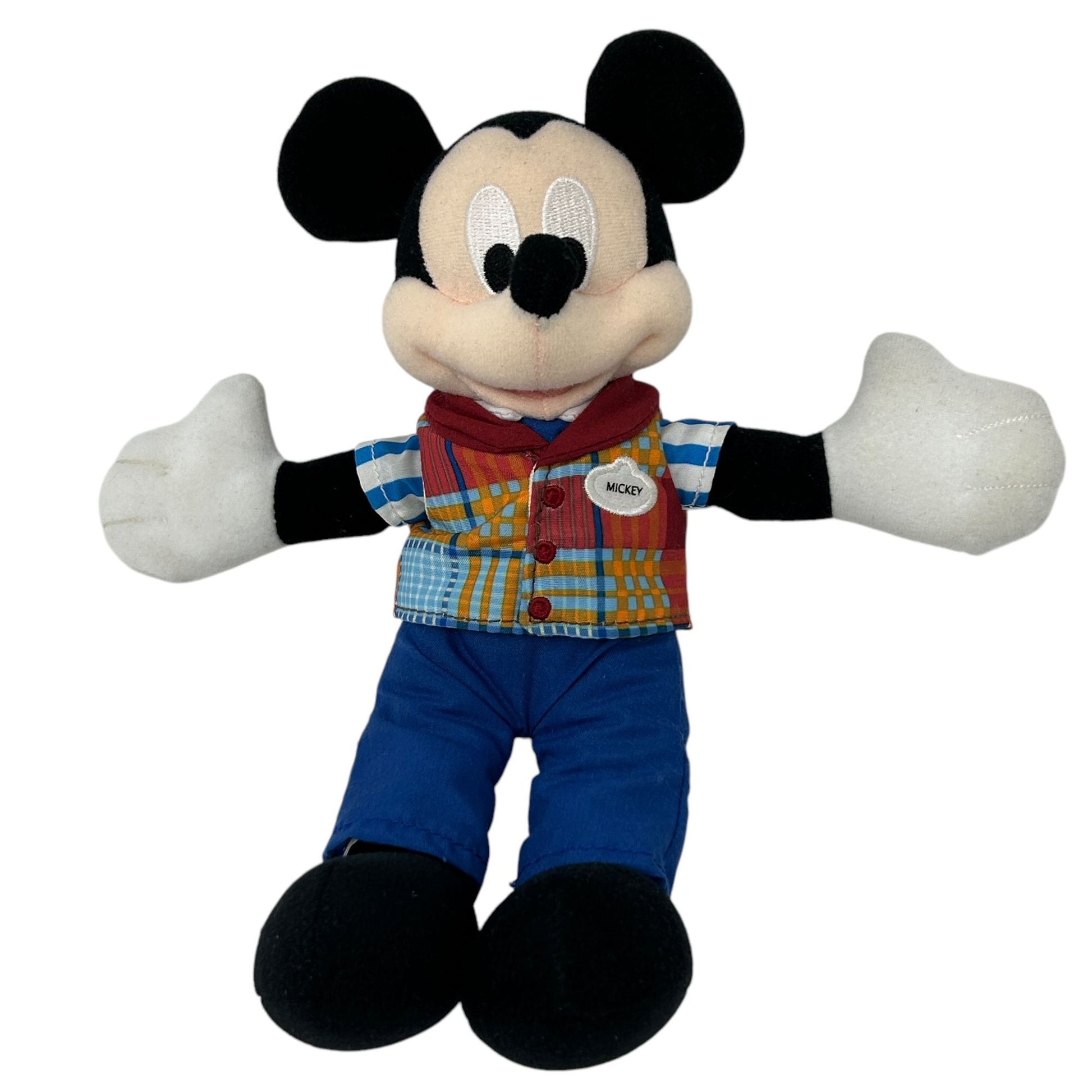 Mickey Mouse plush toy wearing a plaid shirt and blue pants, arms open wide, front view