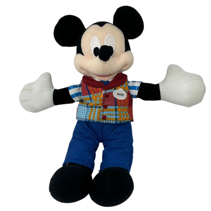 Mickey Mouse plush toy wearing a plaid shirt and blue pants, arms open wide, front view