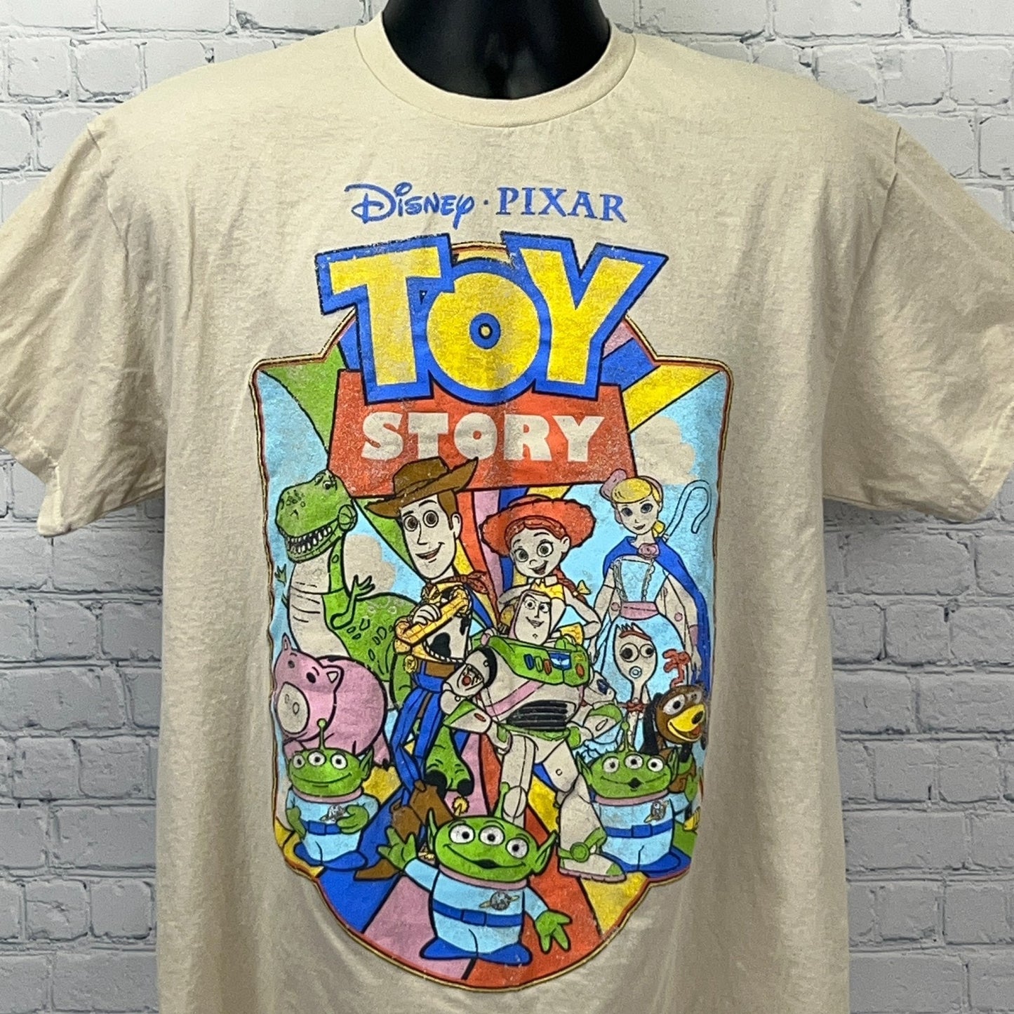 Cream Disney Pixar Toy Story T-shirt featuring colorful characters in a front view design