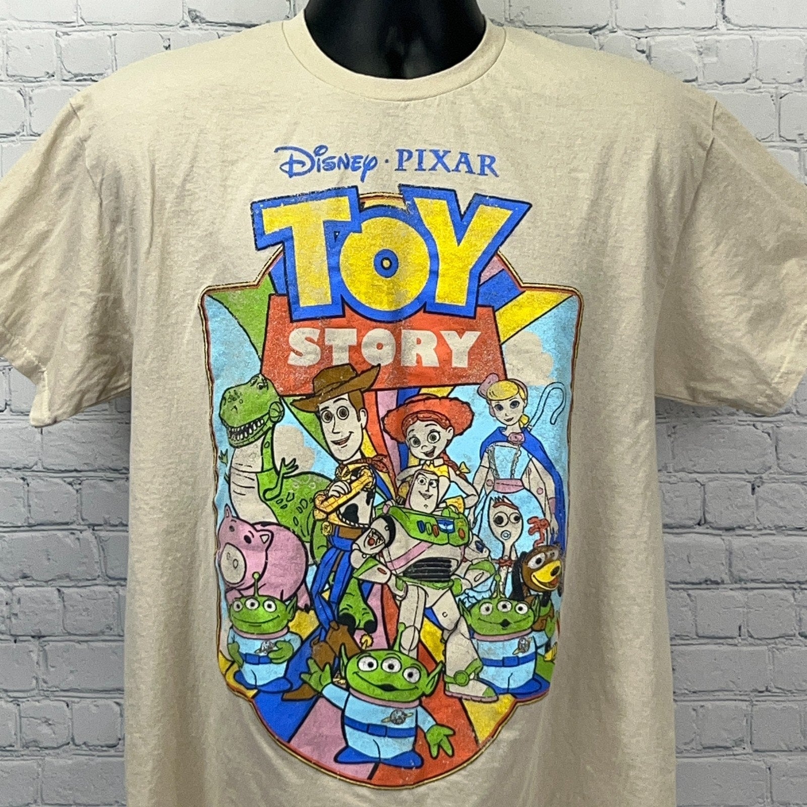 Cream Disney Pixar Toy Story T-shirt featuring colorful characters in a front view design