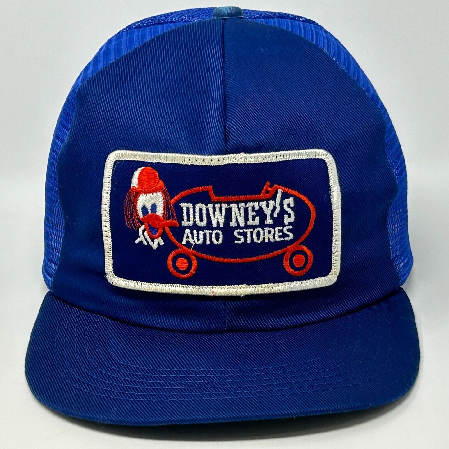 Vintage blue trucker hat with a front logo patch of Downeys Auto Stores featuring a character design