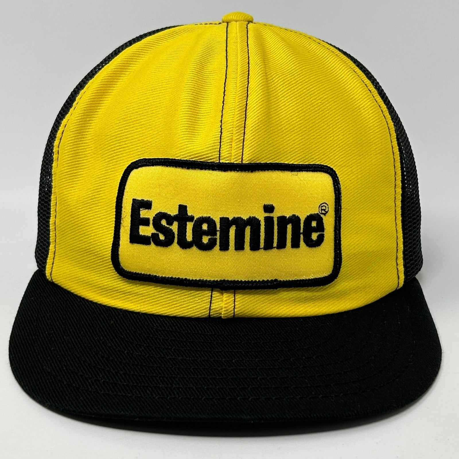 Vintage yellow and black farmer hat with Estemine logo, front view, trucker style