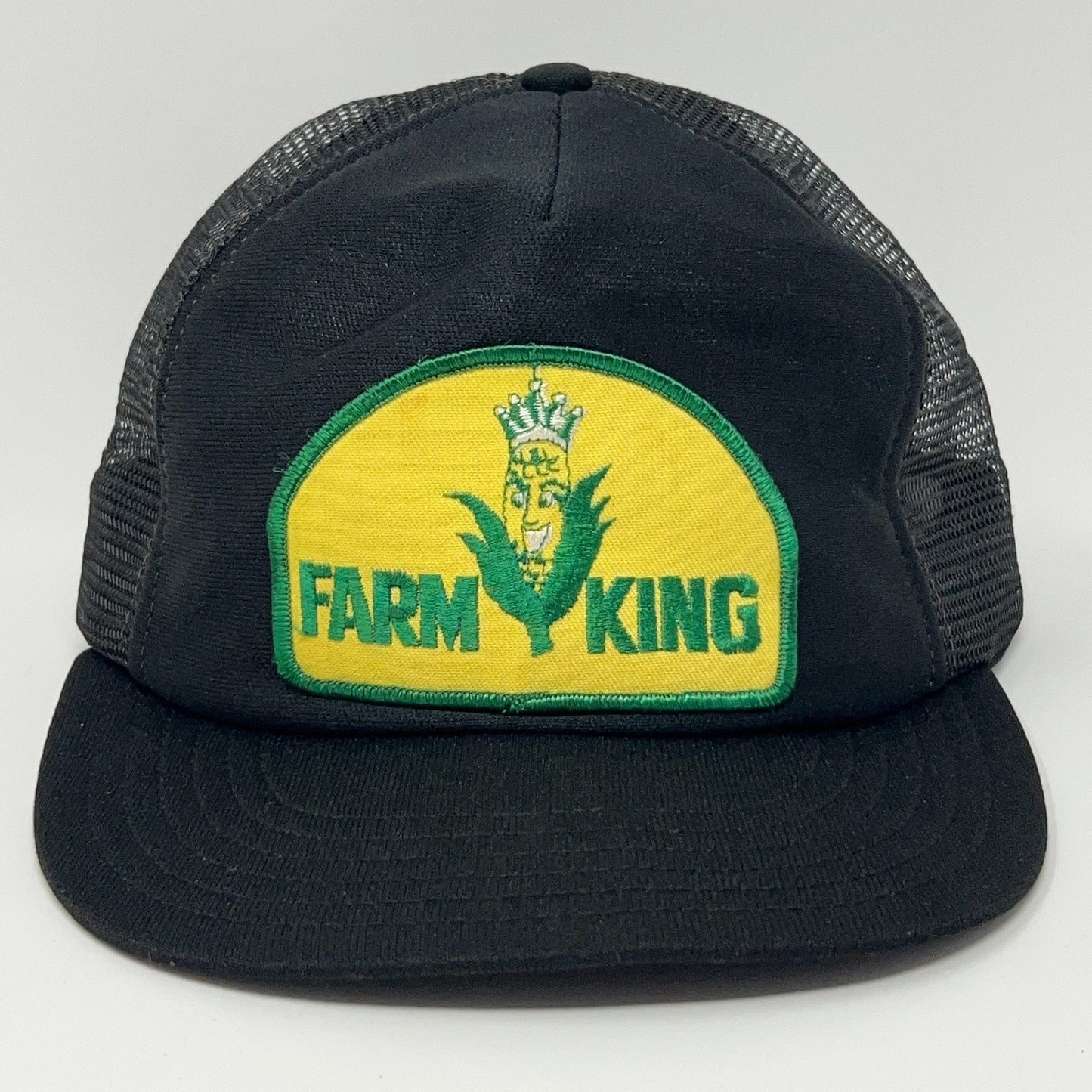 Front view of a black mesh Farm King baseball cap with a yellow and green logo patch