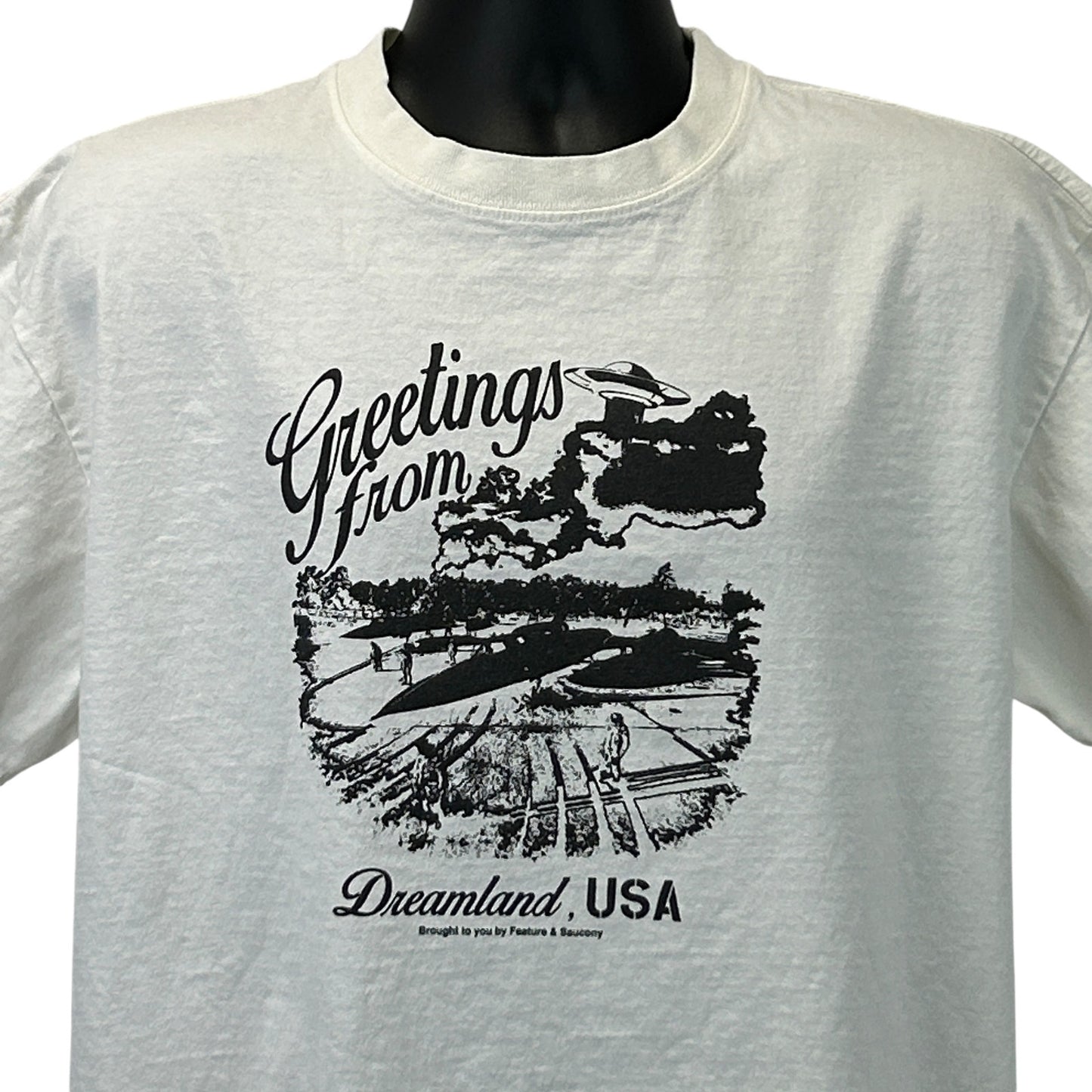 Feature Saucony Graphic T-Shirt in White, Front View with 'Greetings from Dreamland, USA' Print