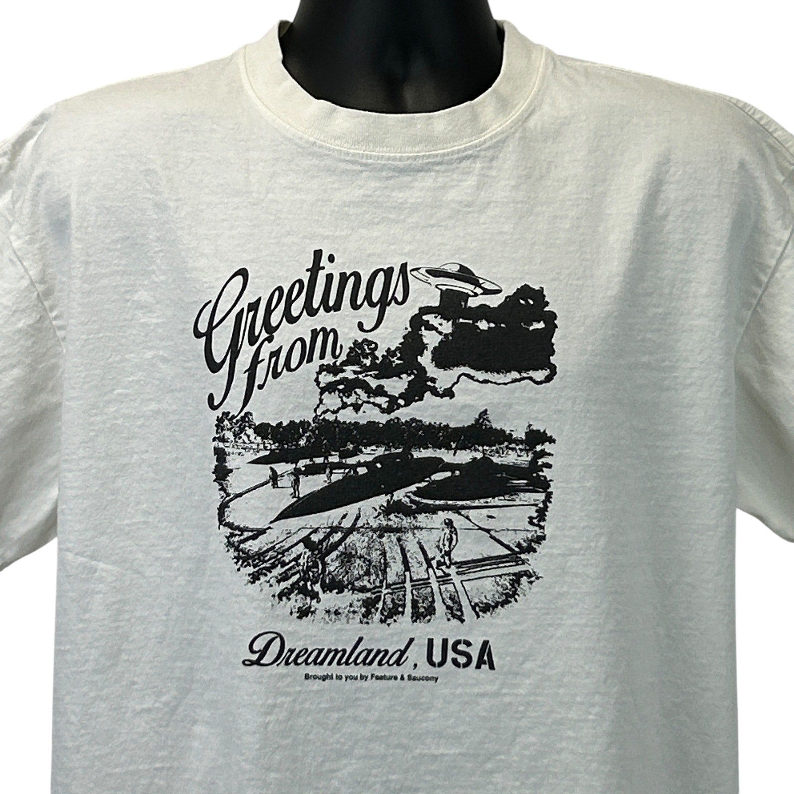 Feature Saucony Graphic T-Shirt in White, Front View with 'Greetings from Dreamland, USA' Print