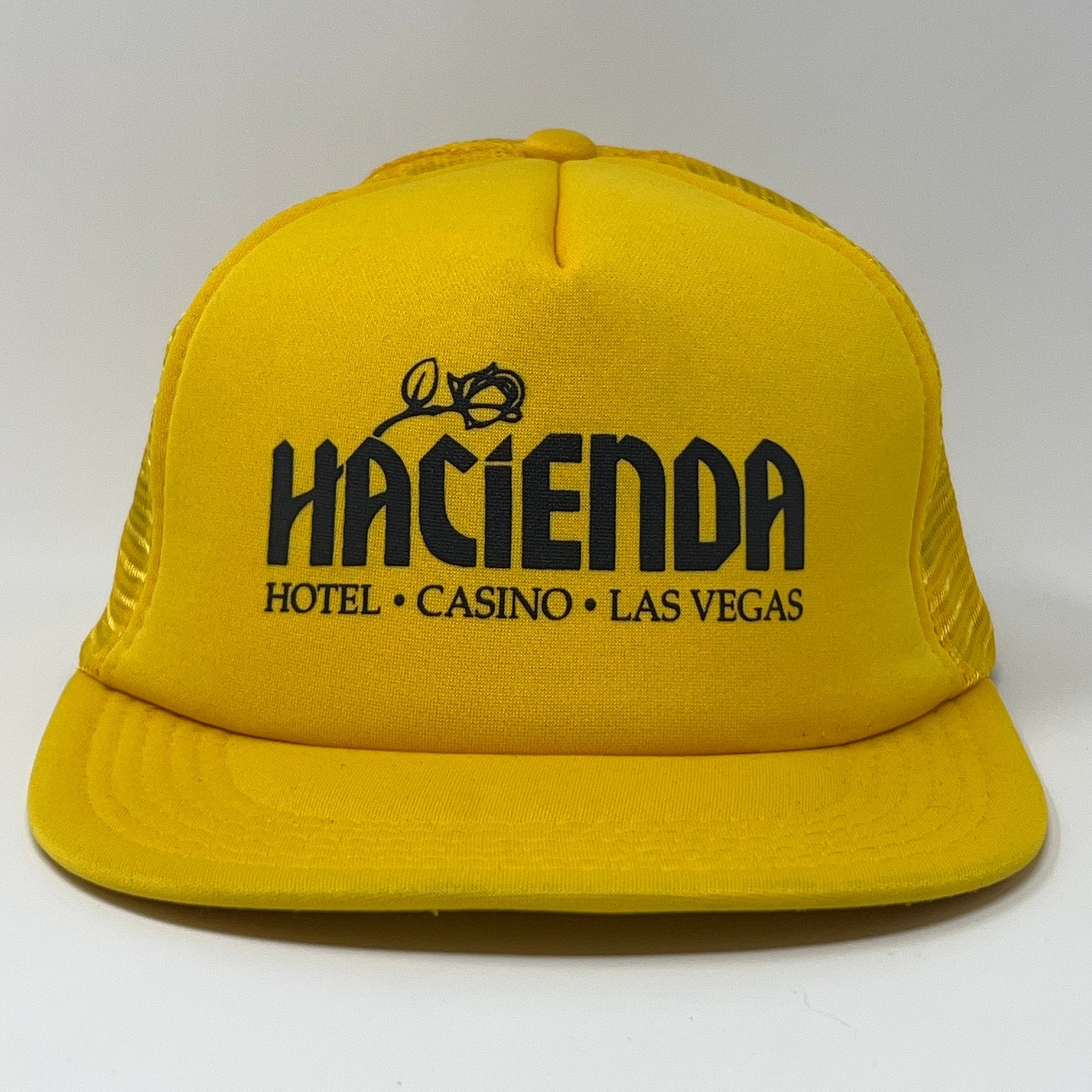 Front view of a yellow Vintage Trucker Hat featuring Hacienda Hotel and Casino logo in black