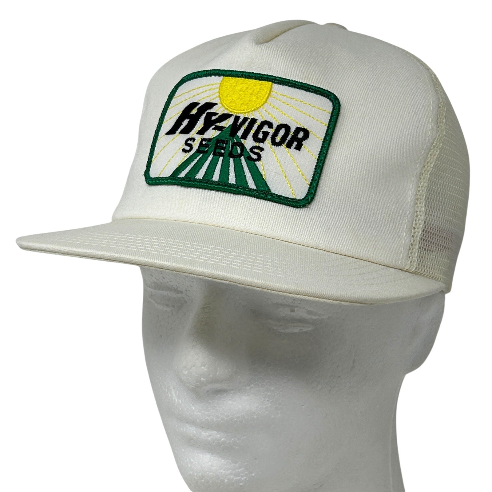 White farmer hat with green and yellow HYVIGOR SEEDS logo on the front, featuring a curved brim