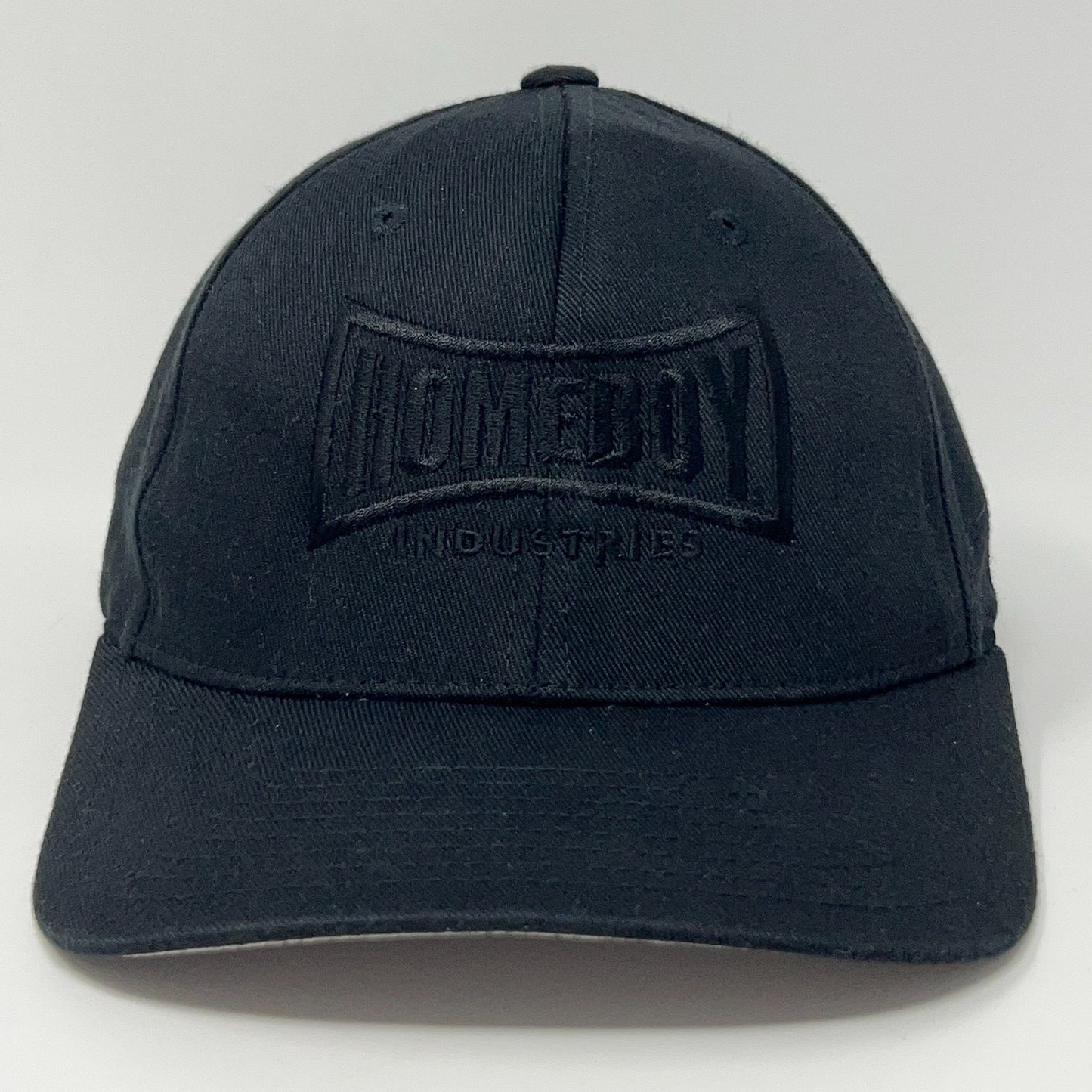 Black Flexfit cap featuring Homeboy Industries logo in front view, adjustable size for comfort