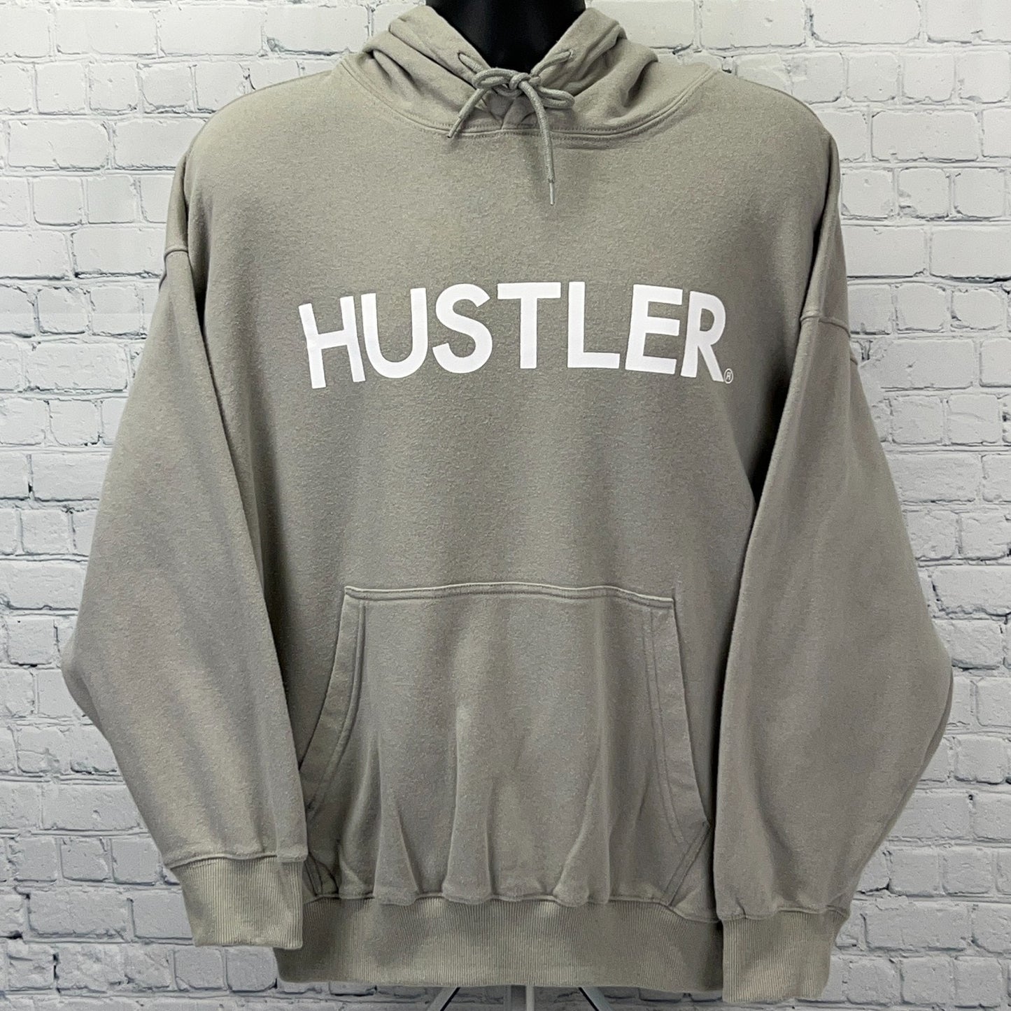 Light gray Hustler hoodie with large white logo on the front and a spacious kangaroo pocket