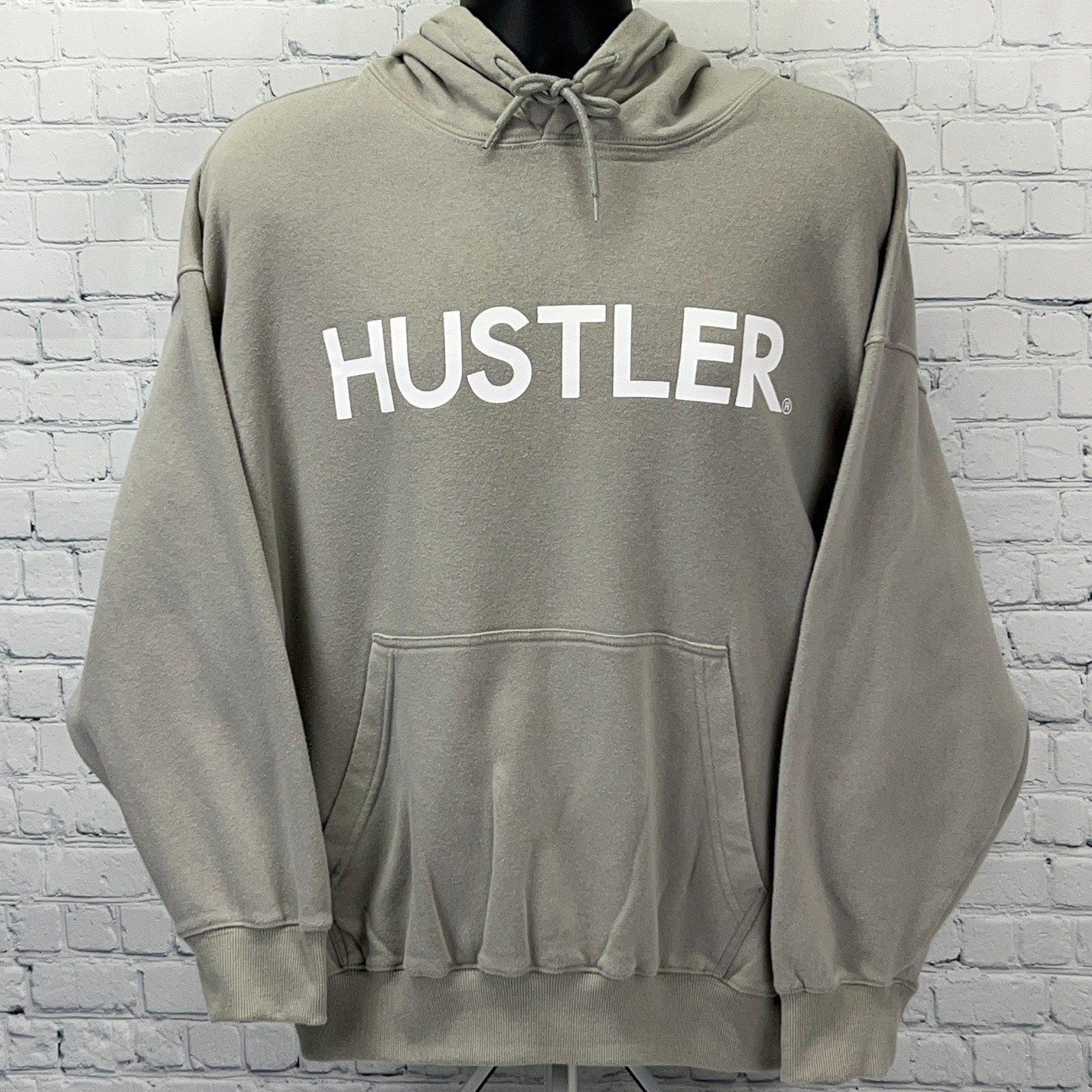 Light gray Hustler hoodie with large white logo on the front and a spacious kangaroo pocket