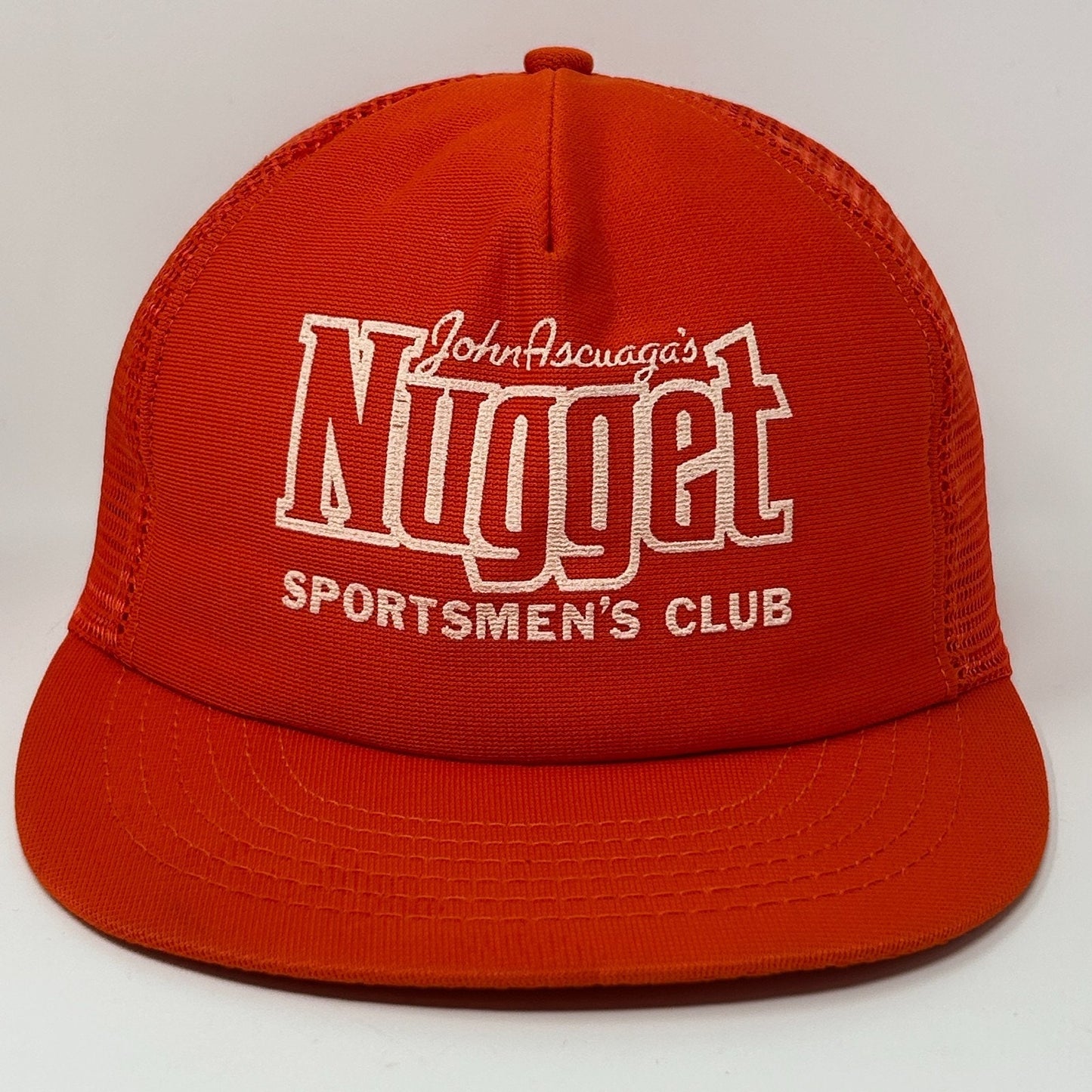 Front view of an orange Vintage Trucker Hat featuring John Ascuaga's Nugget Sportsmen's Club logo