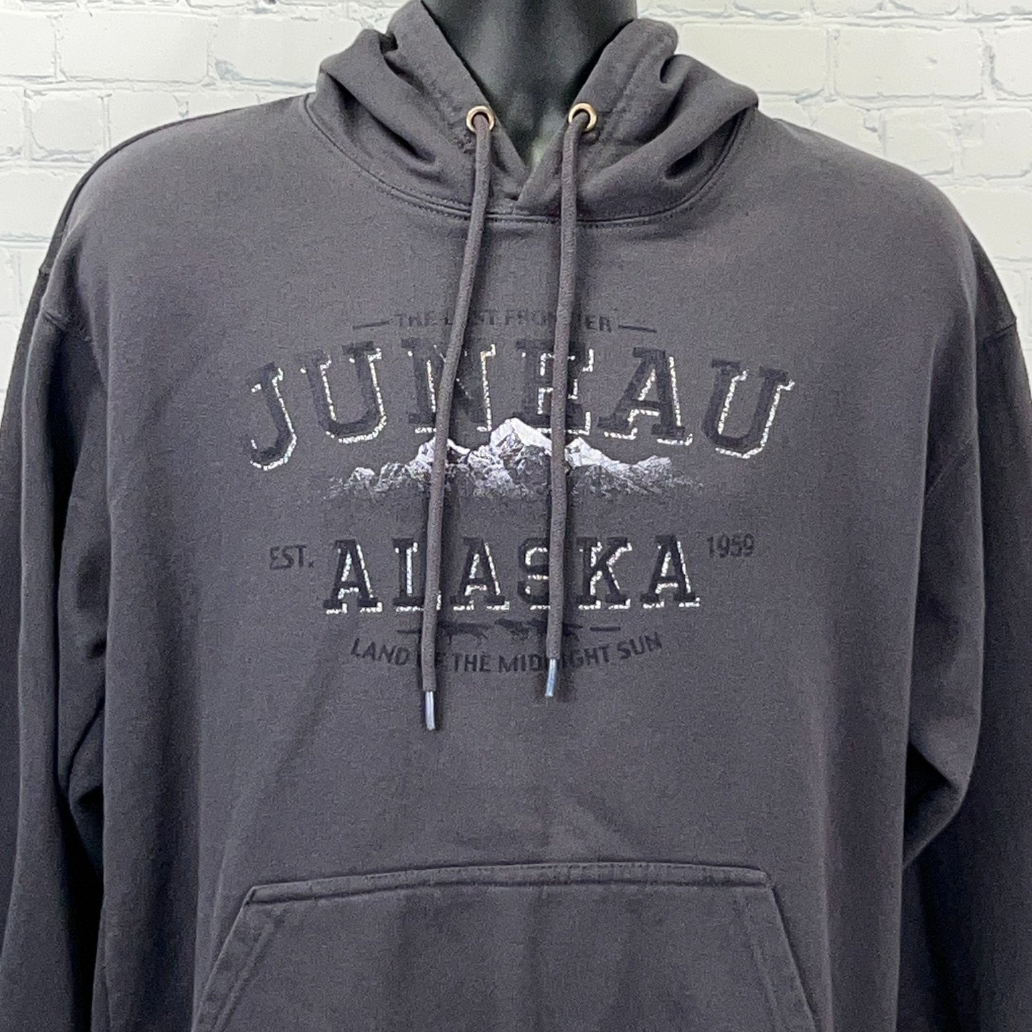 Front view of a charcoal gray hoodie featuring Juneau Alaska logo with mountains and established date