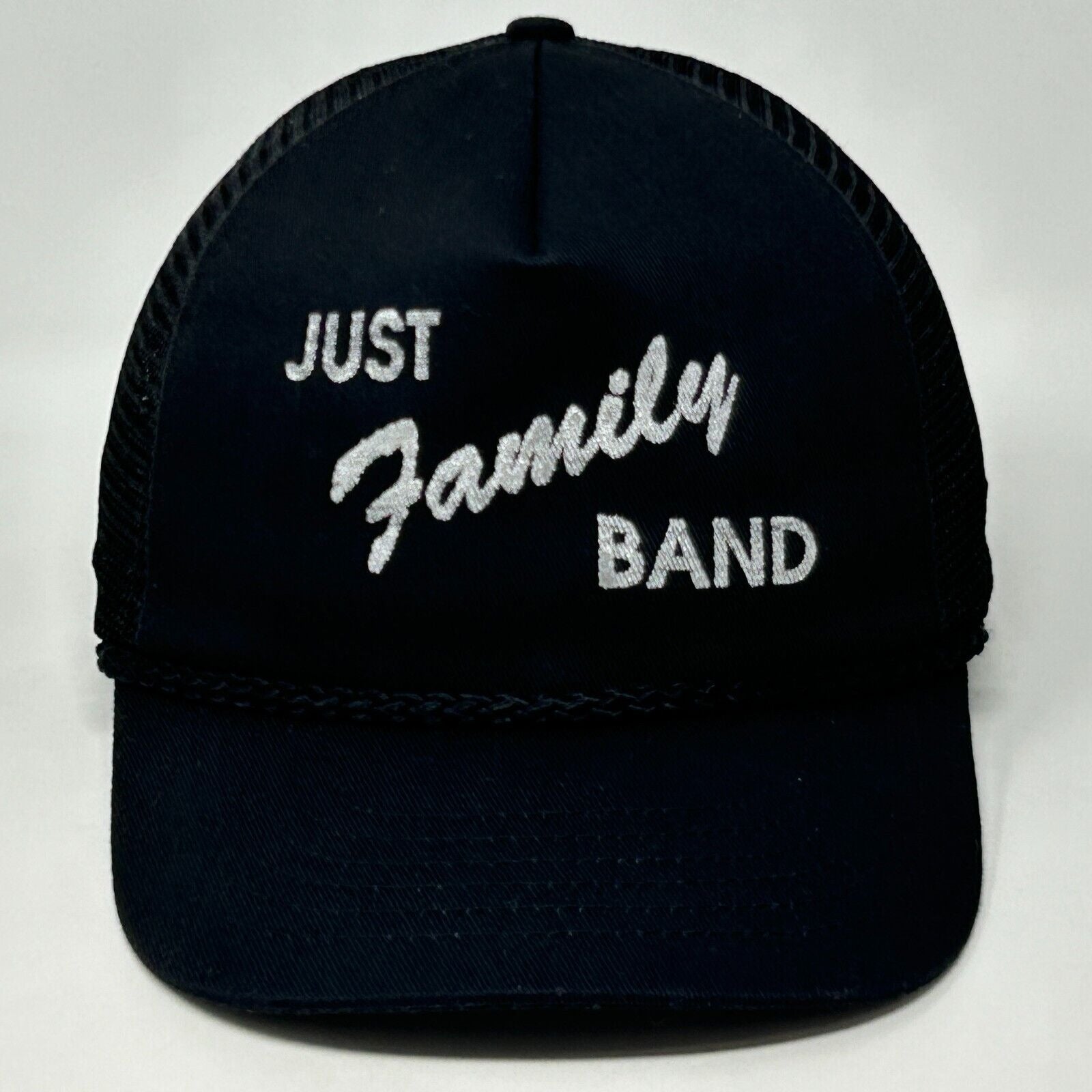 Front view of a black Vintage trucker hat with Just Family Band logo in white