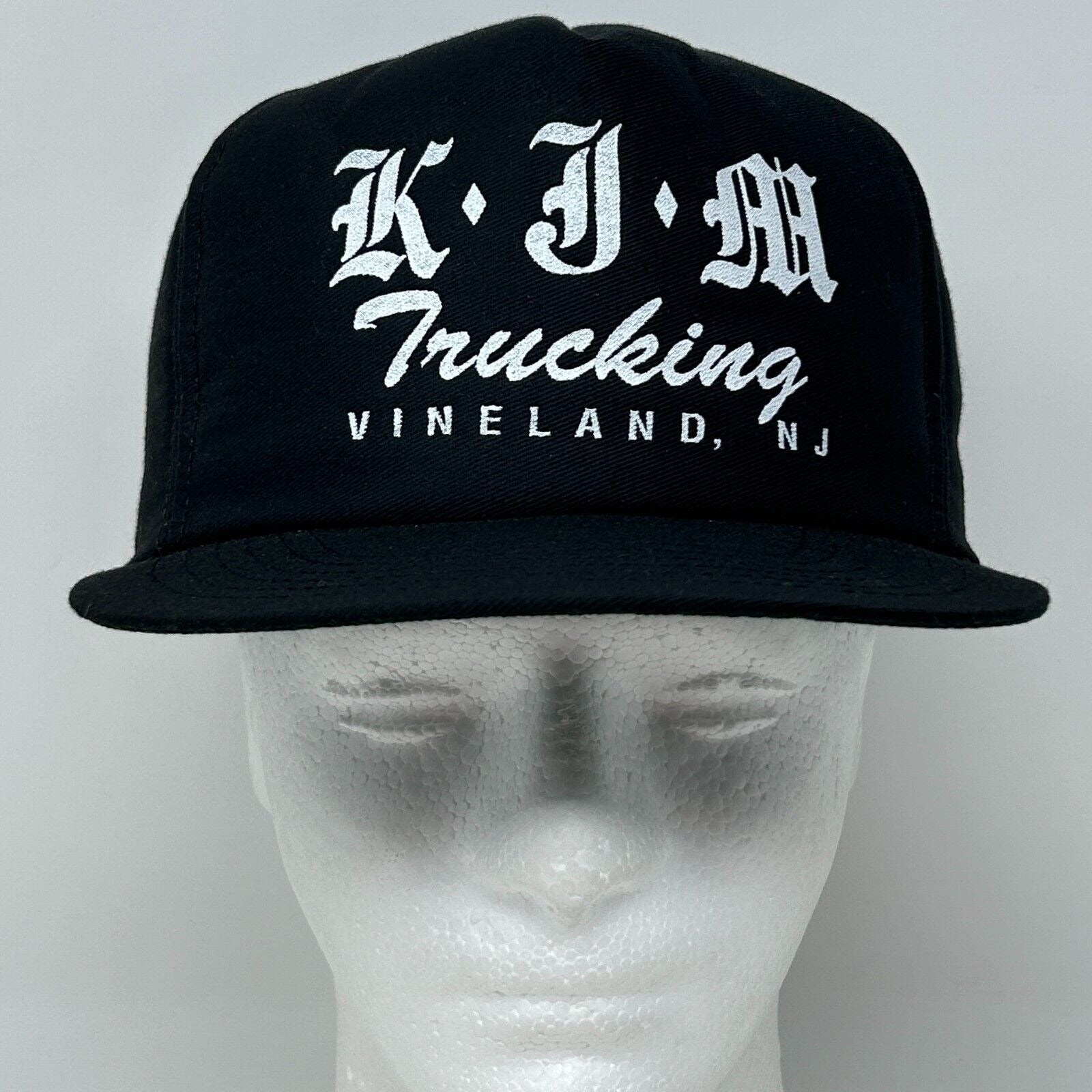 Black vintage cap featuring KJM Trucking logo in white, front view with adjustable strap