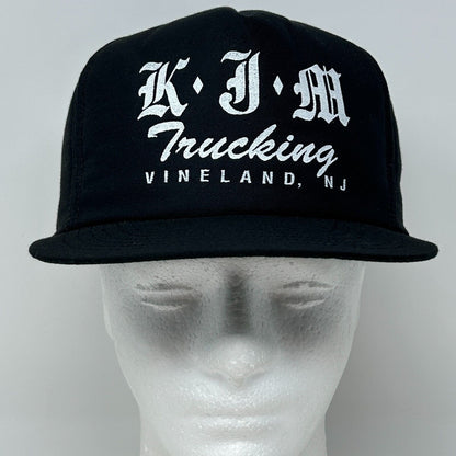 Black vintage cap featuring KJM Trucking logo in white, front view with adjustable strap