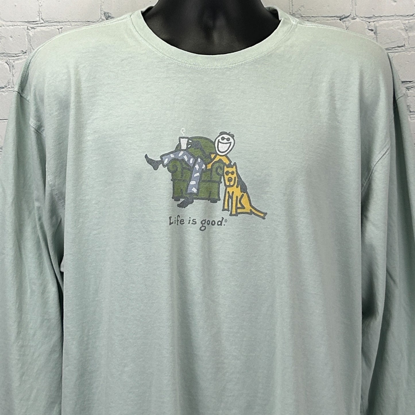 Front view of light green Life Is Good T Shirt with couch graphic and smiling character