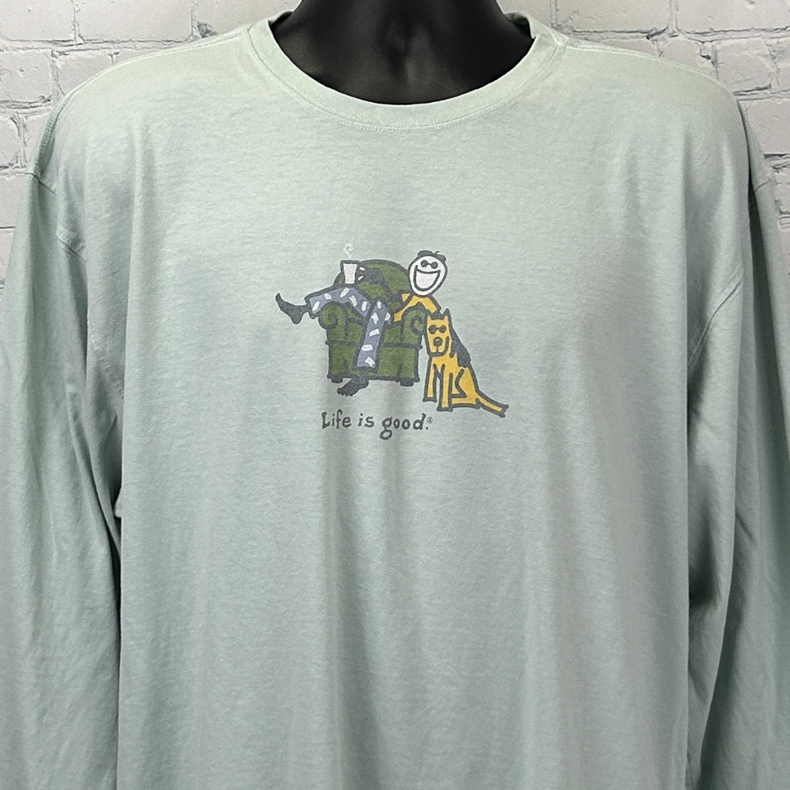 Front view of light green Life Is Good T Shirt with couch graphic and smiling character