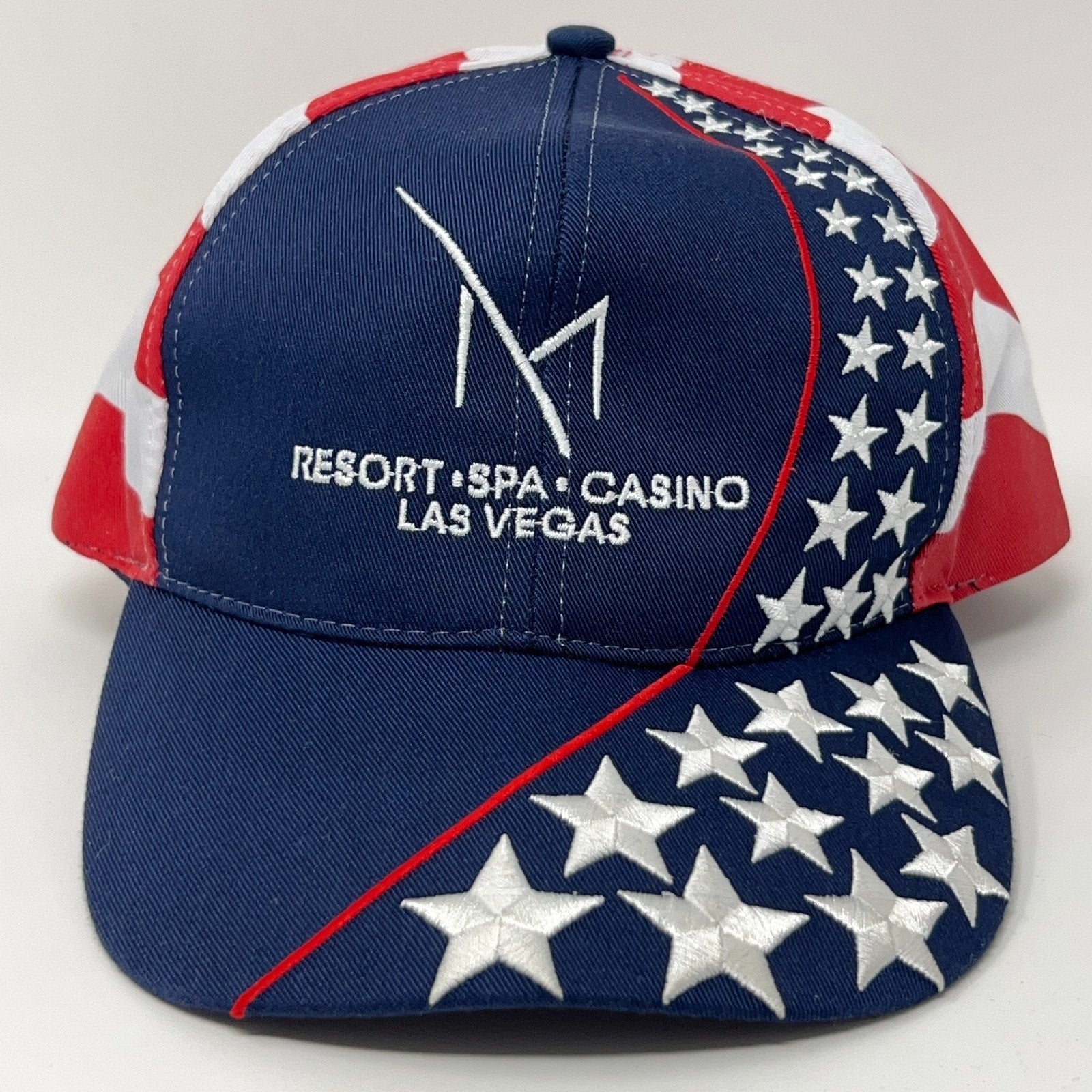 M Resort Hat in navy blue with red and white star accents, featuring logo and casino details on the front