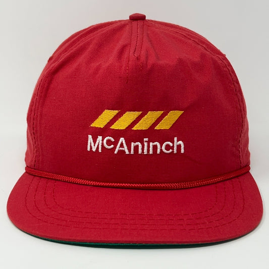 Red vintage McAninch Corporation cap featuring logo with yellow stripes and a flat brim