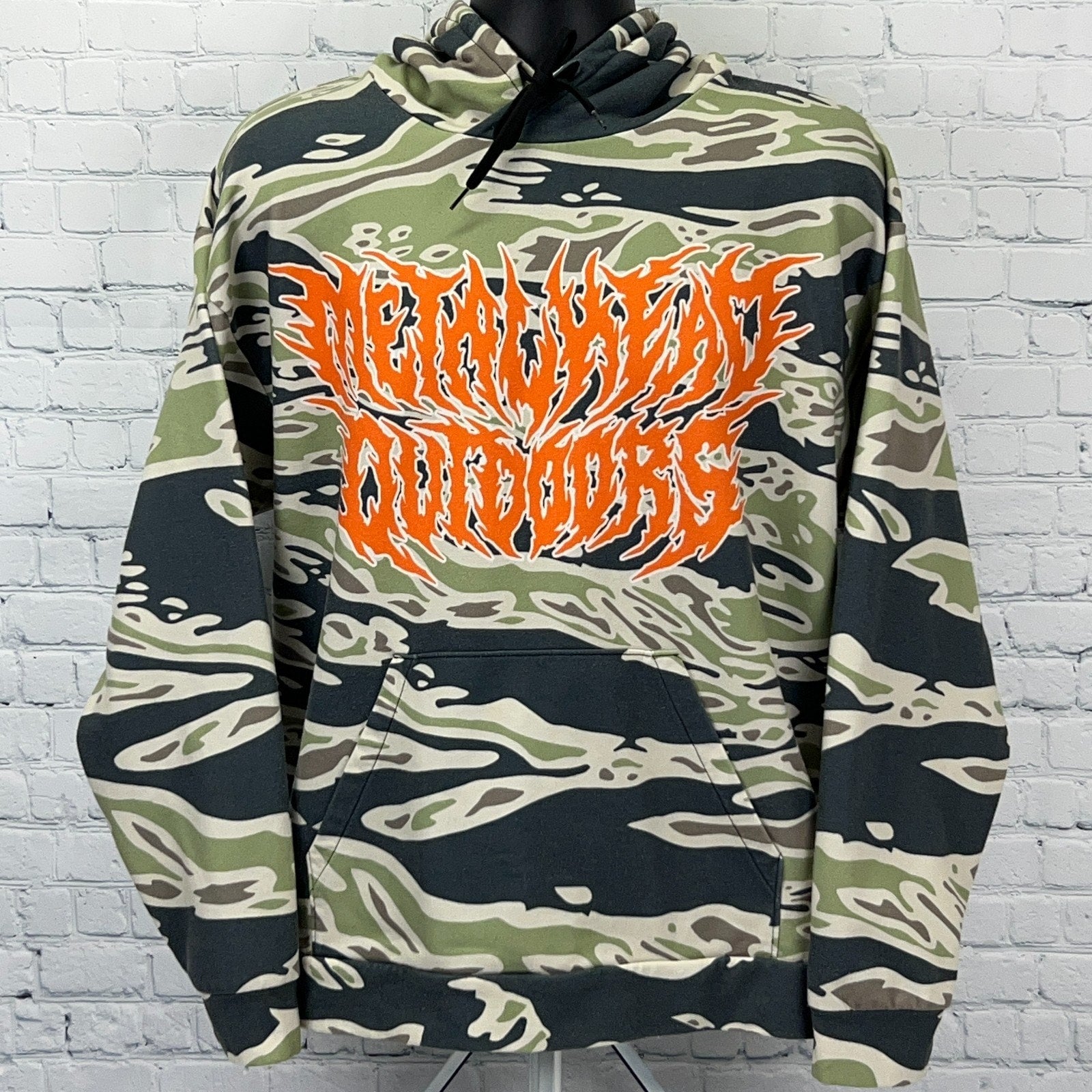 Metalhead Outdoors hooded sweatshirt in green camo with bold orange logo on the front
