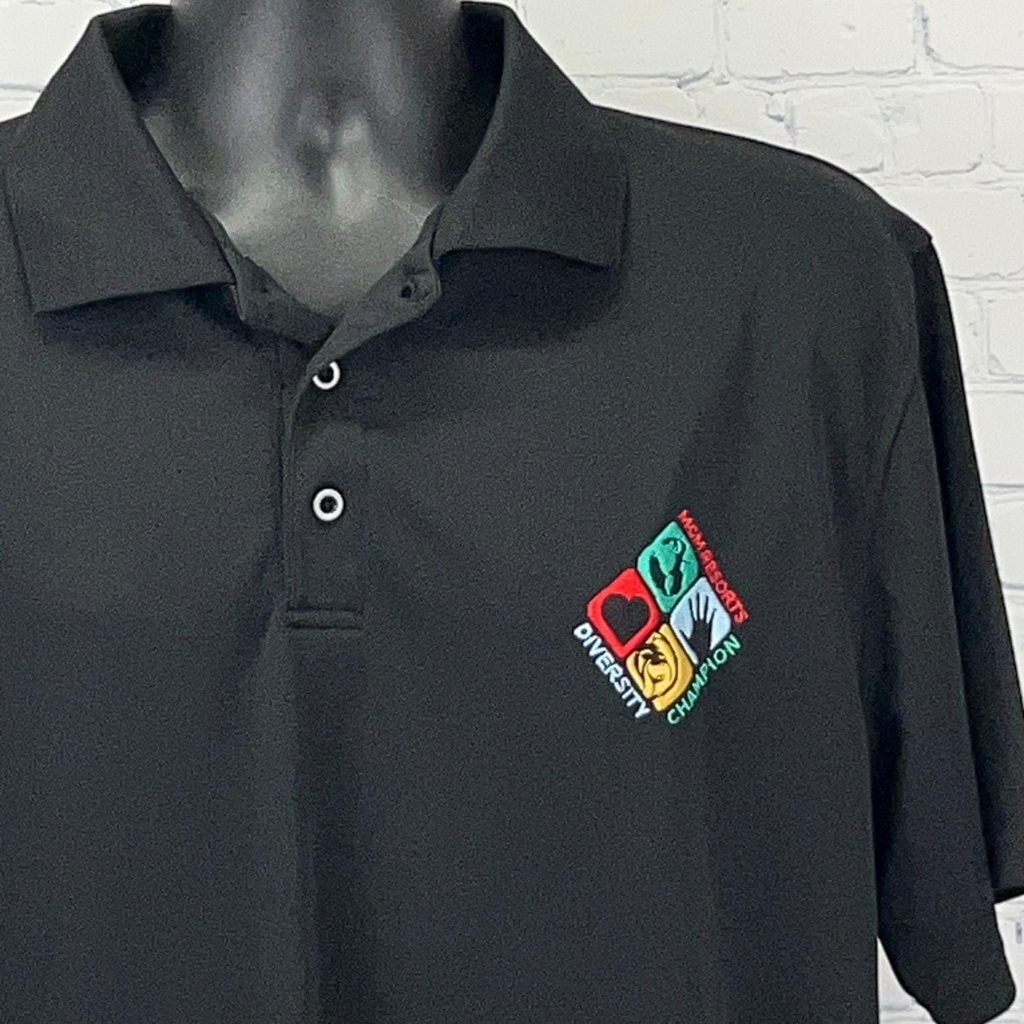 Black MGM Resorts polo shirt with colorful logo featuring the words diversity and champion, front view