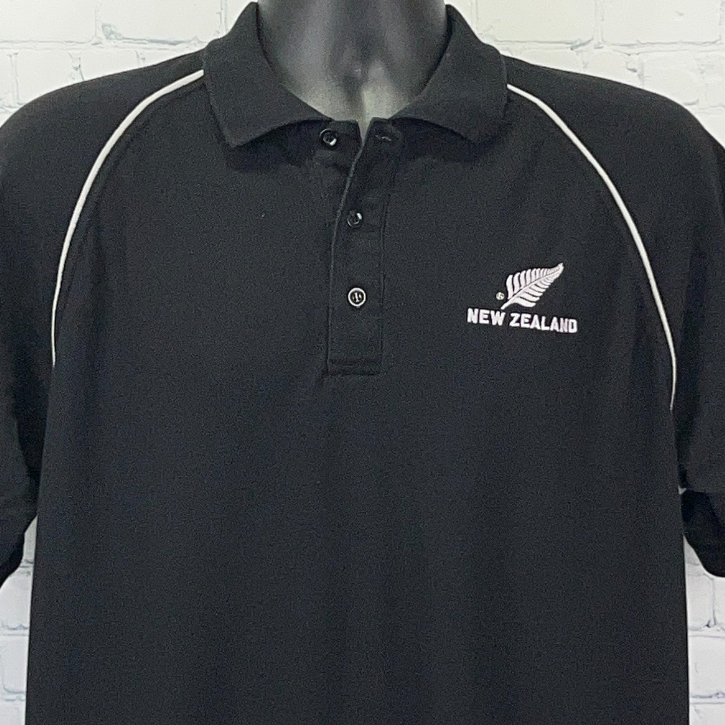 Black polo shirt from The Fern Brand with New Zealand All Blacks logo in front and contrast white stitching