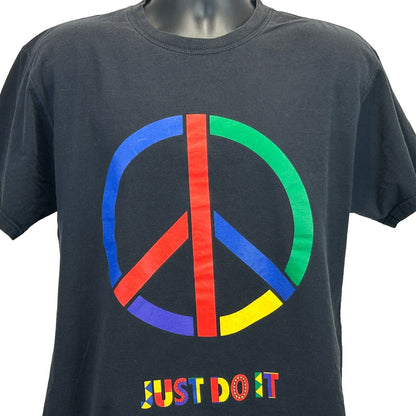 Nike T-Shirt in black featuring a colorful peace sign graphic and Just Do It logo on the front
