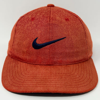 Nike cap in orange with a dark blue Nike logo on the front, showcasing a relaxed fit style.