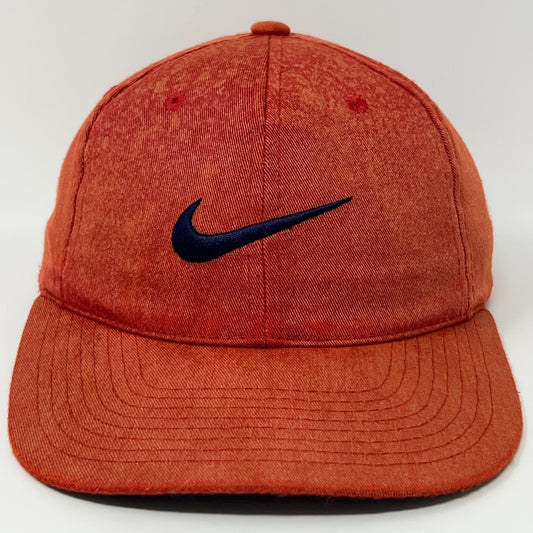 Nike cap in orange with a dark blue Nike logo on the front, showcasing a relaxed fit style.