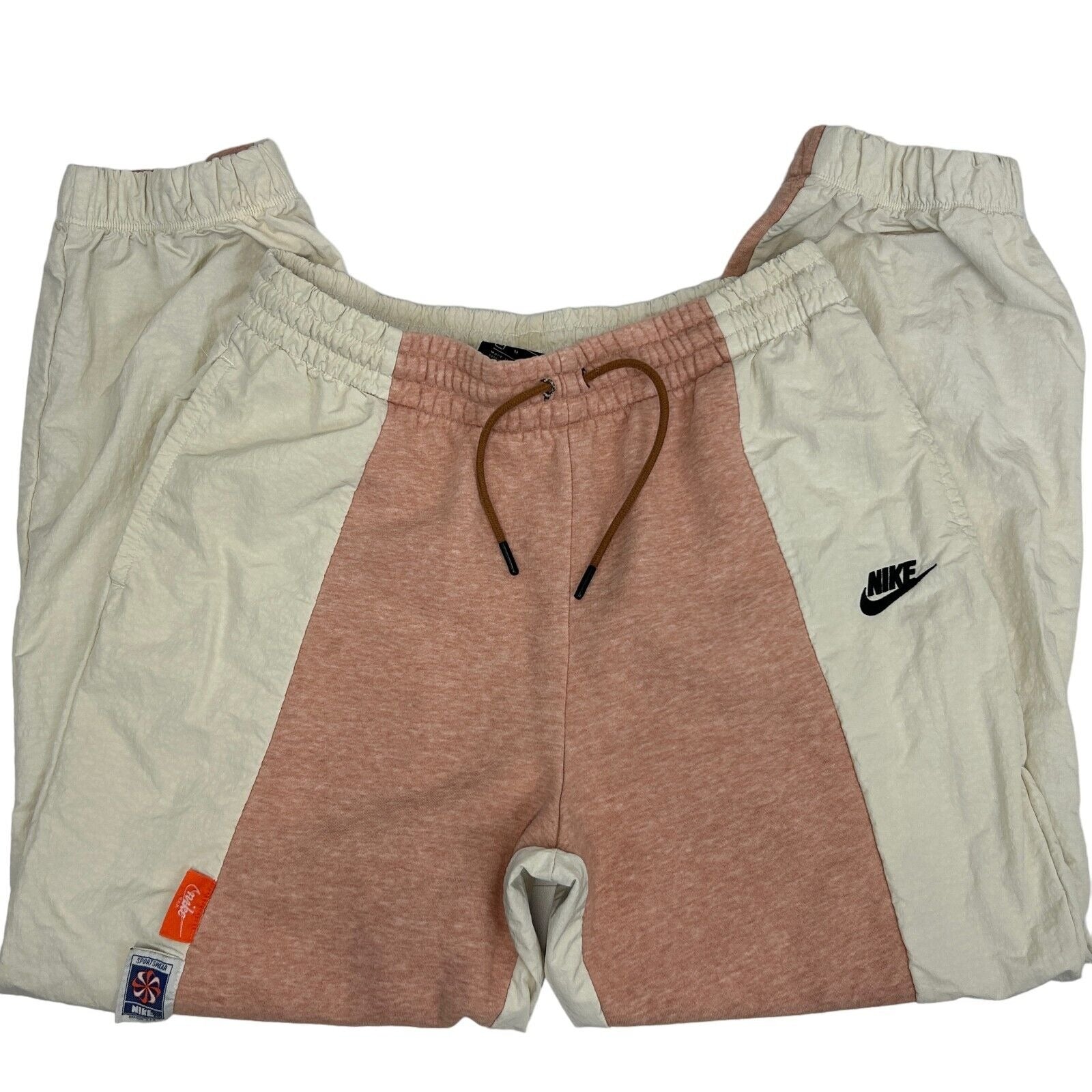 Nike sweatpants in peach and cream color, featuring adjustable drawstring and logo on the left thigh