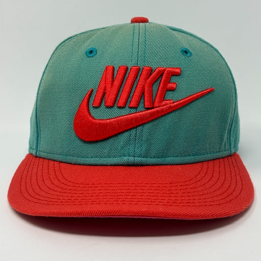 Front view of Nike teal and red snapback hat featuring bold Nike logo and contrasting visor