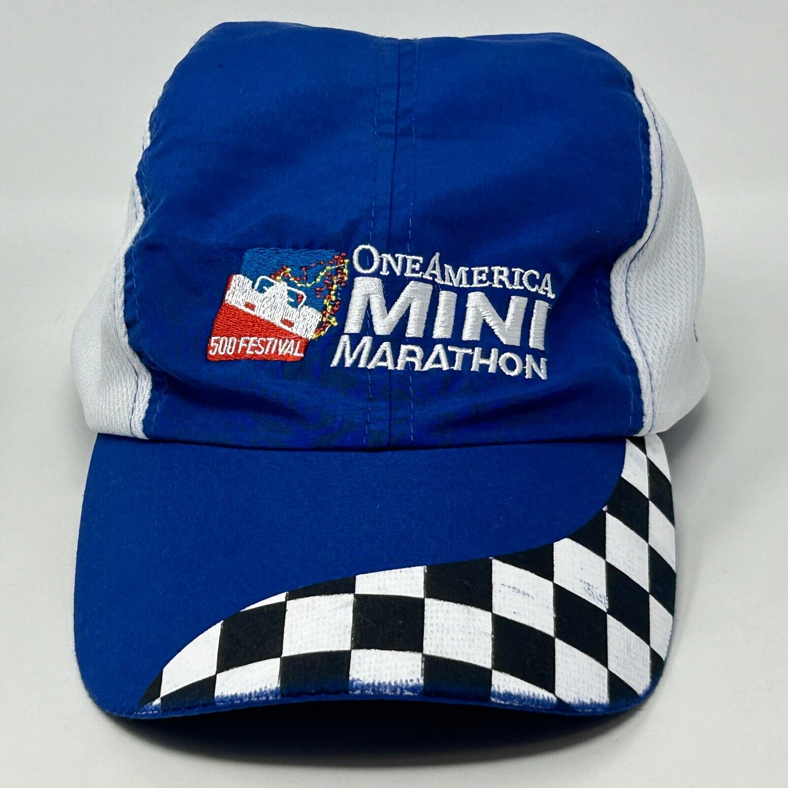 Front view of the blue One America 500 cap featuring a checkered pattern and festival logo