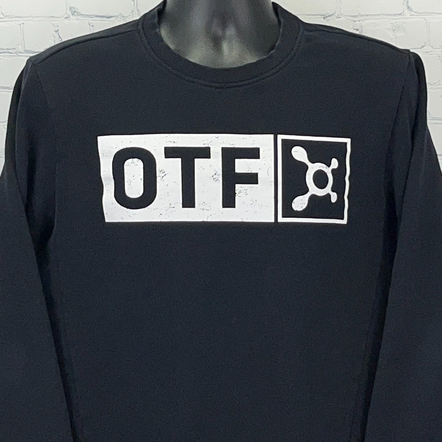 Front view of black Orangetheory long sleeve shirt featuring white OTF logo prominently displayed